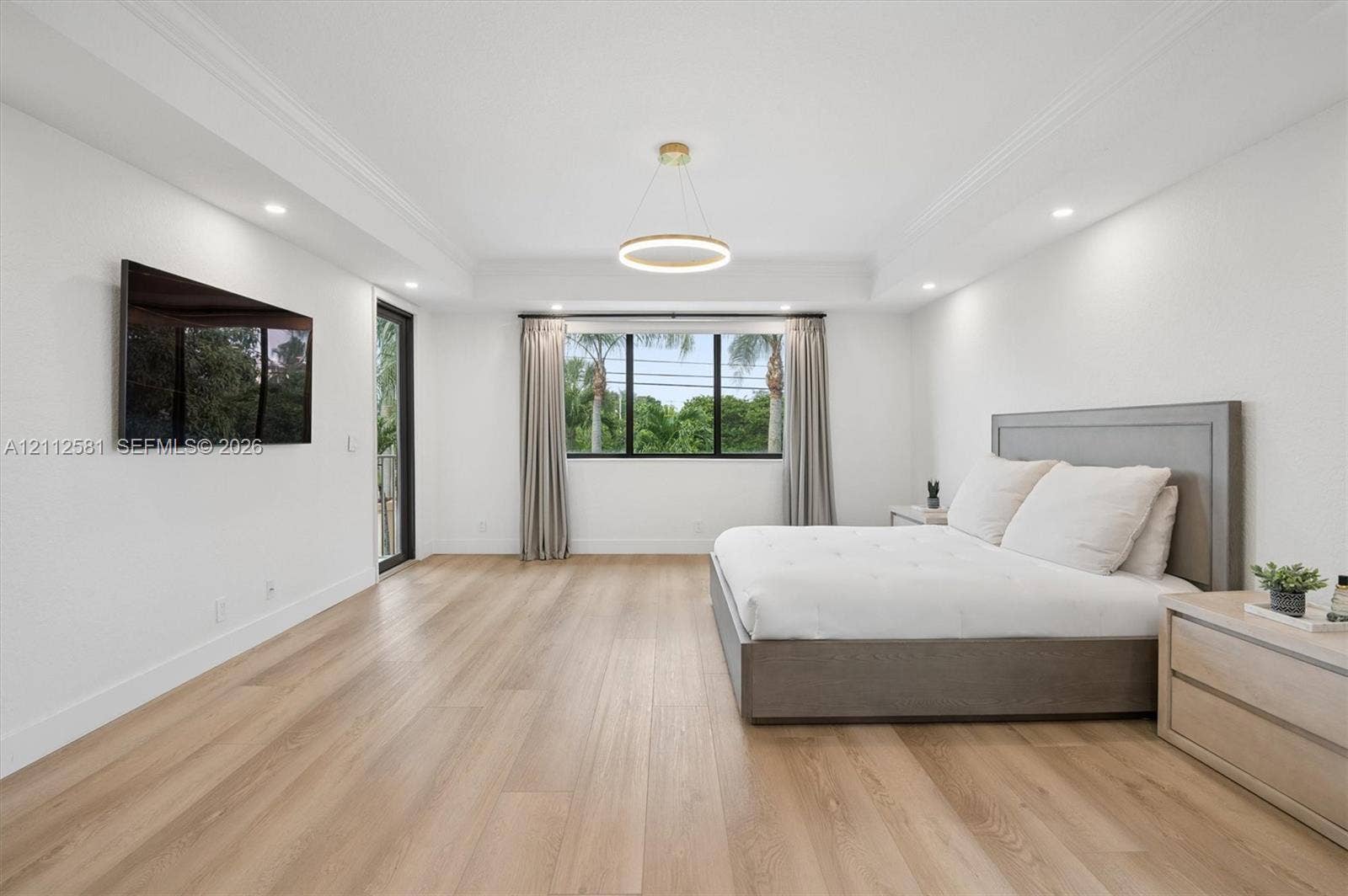 Tray ceiling with recessed lighting, wood-finish flooring, central circular pendant fixture, and large multi-pane windows