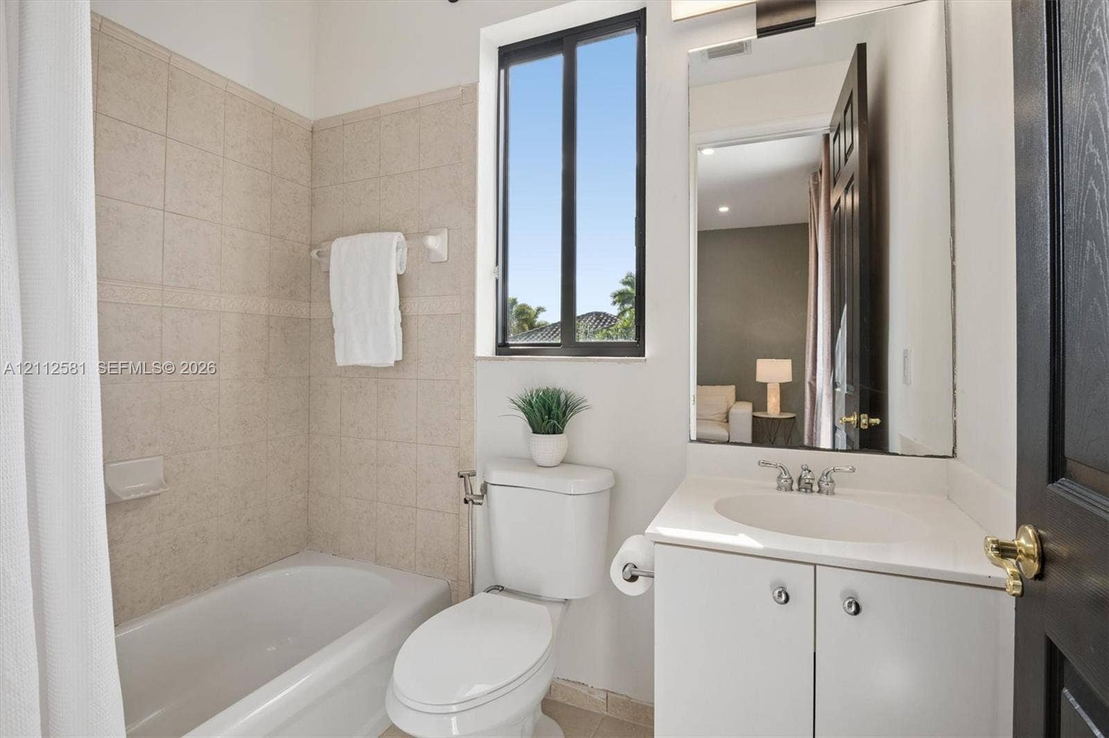 Bathroom featuring a white vanity with a composite countertop, an undermount sink with a polished chrome faucet, a wall-mounted mirror, and a tiled shower-tub combination