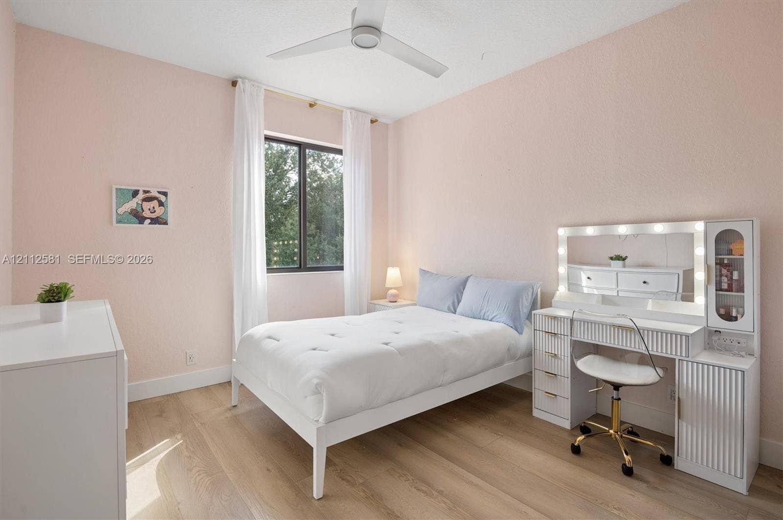 Wood-finish flooring, multi-blade ceiling fan, and window with dark-toned framing