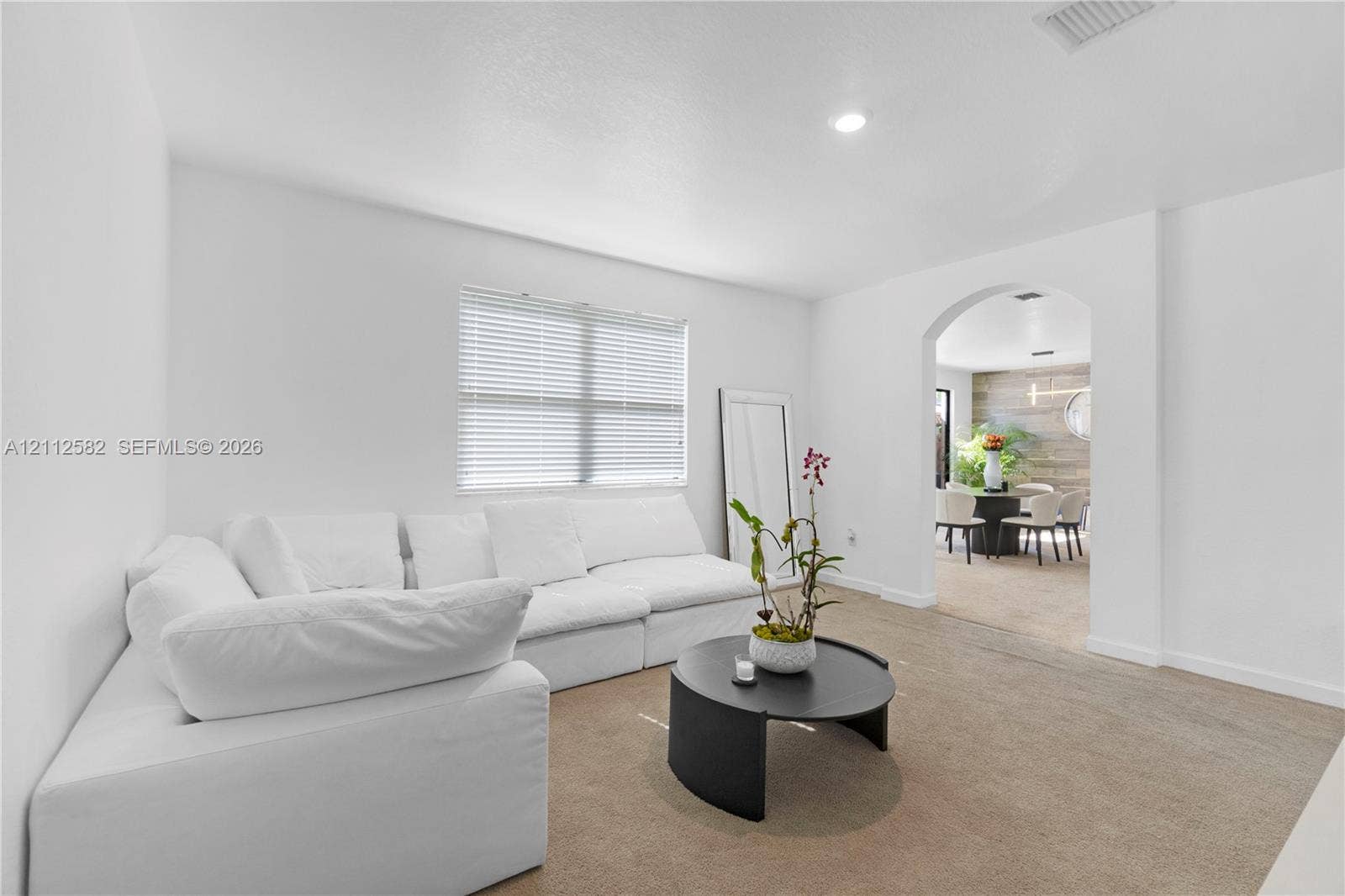 Neutral interior space featuring recessed lighting, a wide arched architectural opening, and horizontal window blinds