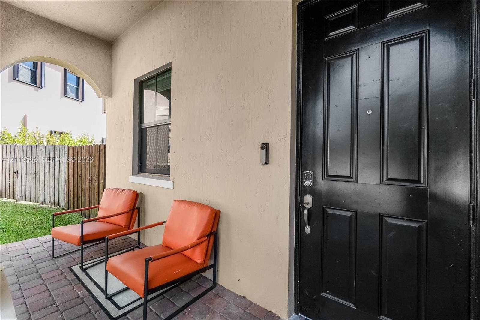 Covered entryway featuring a paver patio, arched ceiling detail, and a paneled entry door with hardware