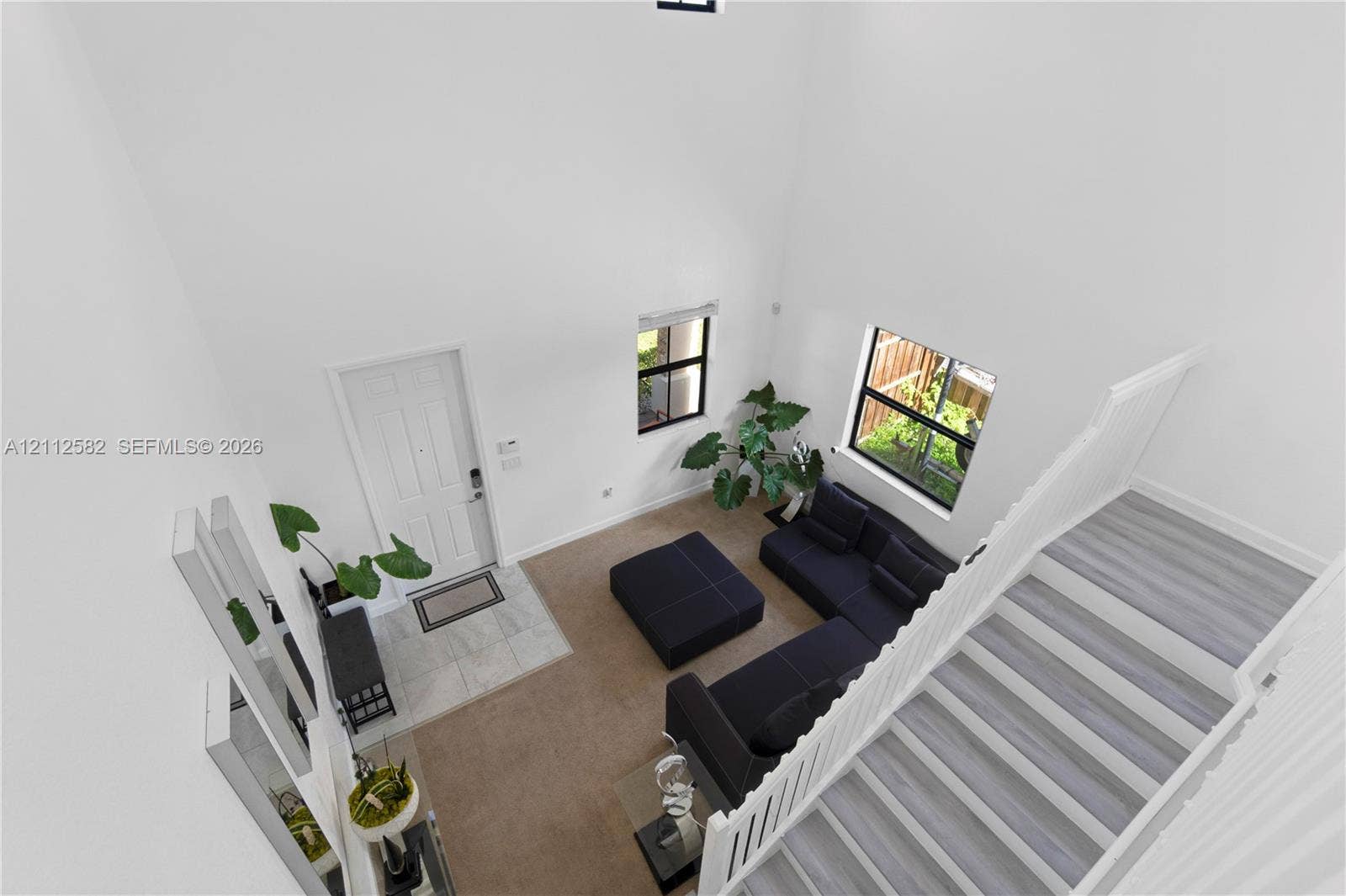 High-ceilinged entry featuring a white paneled door with tile flooring, wood-finish staircase treads, and white vertical balusters