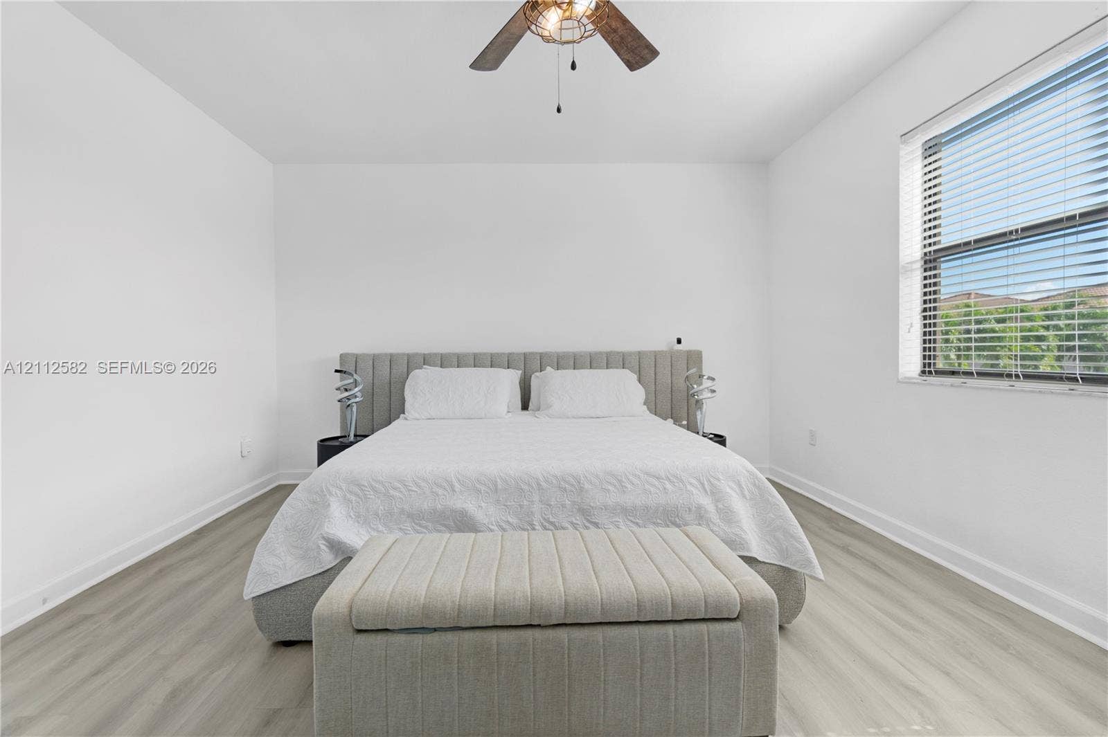 Neutral-toned wood-finish flooring, white walls, and a ceiling-mounted light fixture with a fan