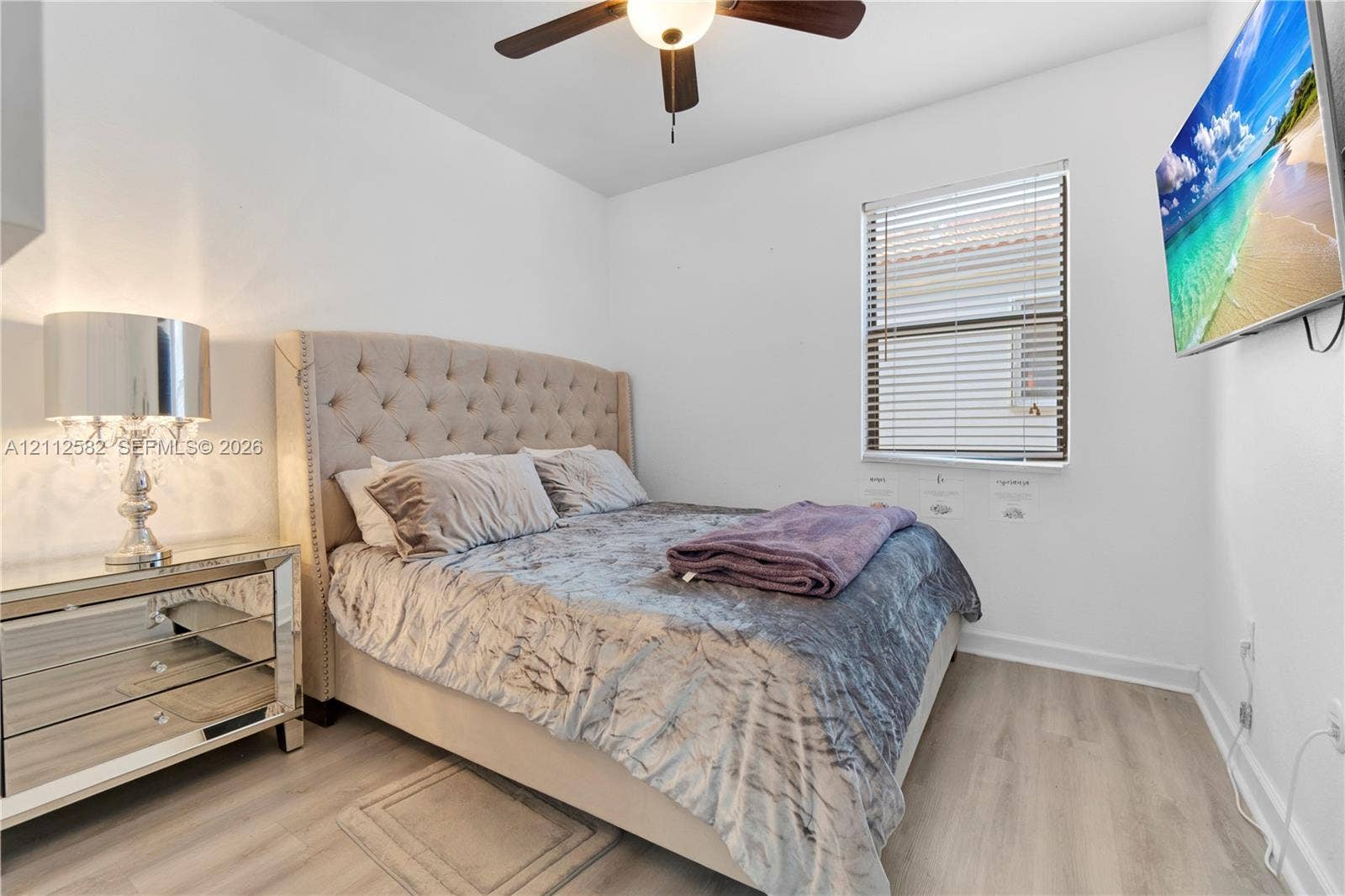Neutral-toned wood-finish flooring, ceiling fan with integrated lighting, and horizontal window blinds