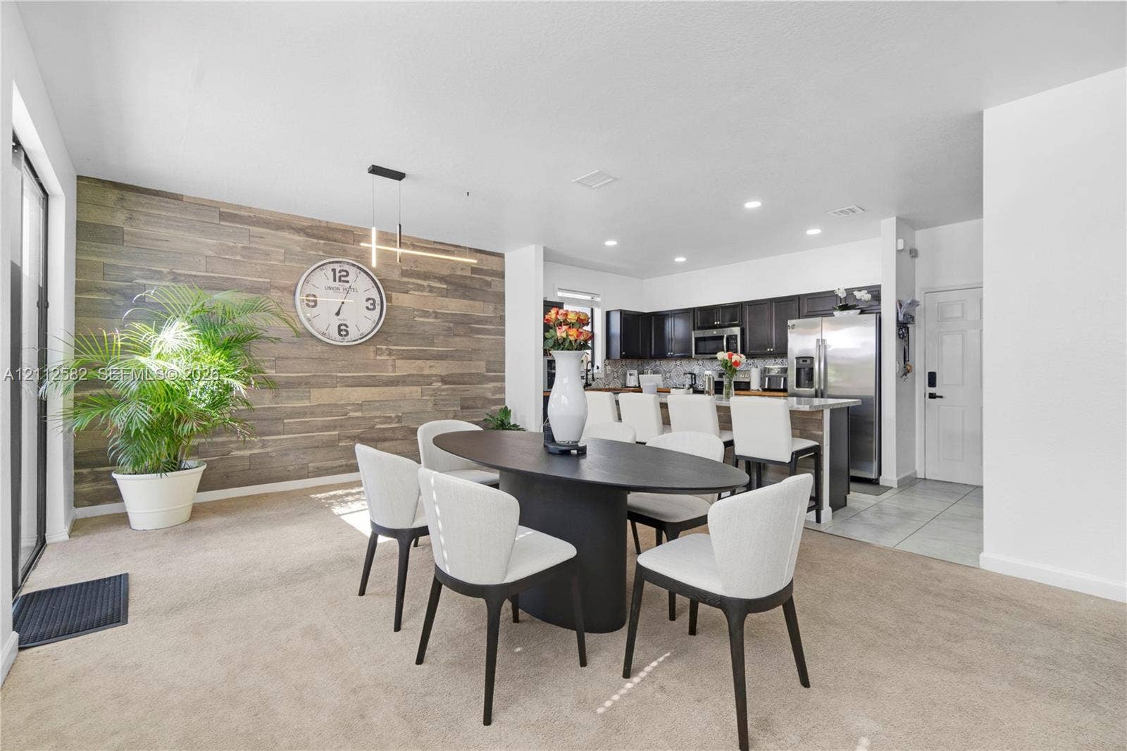 Open-concept area featuring a rustic wood-plank accent wall, recessed lighting, and a breakfast bar with built-in cabinetry and stainless steel appliances