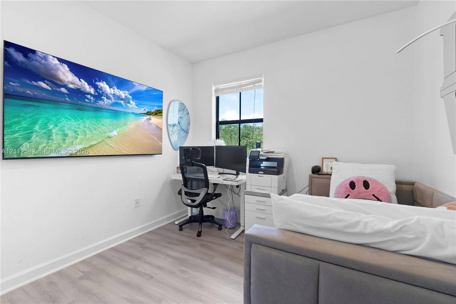 Neutral-toned wood-finish flooring, white walls, and a window featuring a black frame