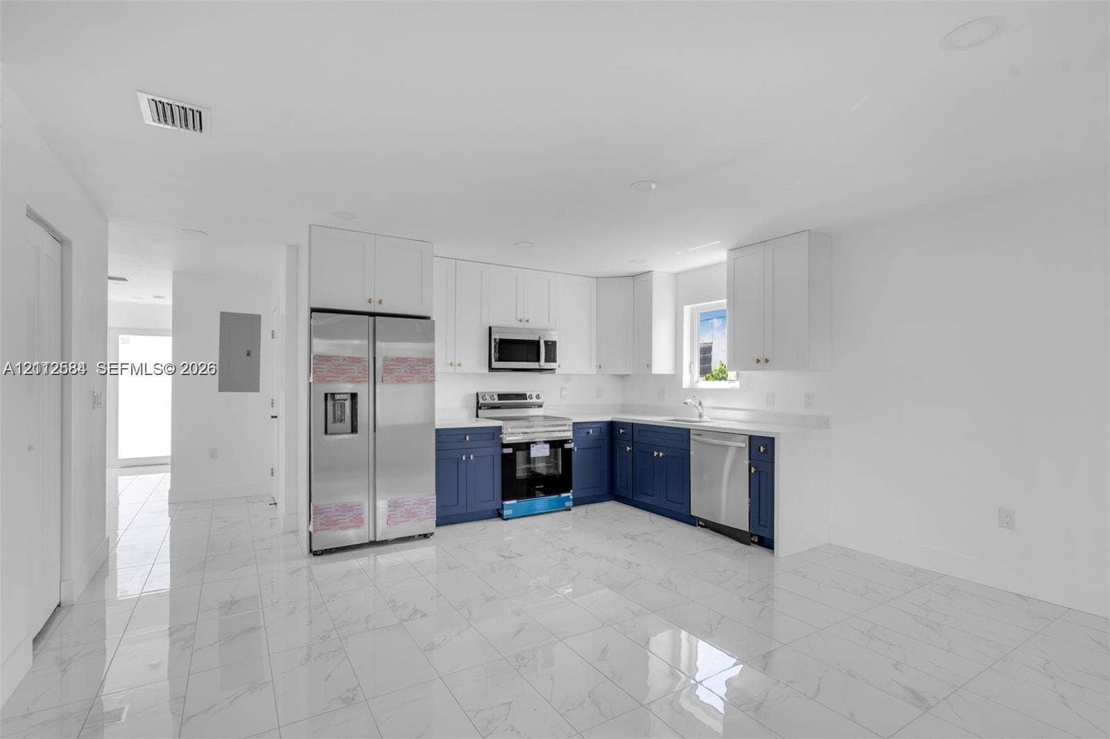 1629 NW 40th Street, Miami, FL 33142 Kitchen featuring two-tone cabinetry, stainless steel appliances, quartz countertops, and white tile flooring