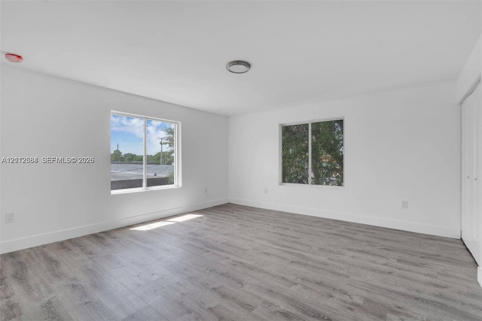 1629 NW 40th Street, Miami, FL 33142 Spacious room featuring wood-finish flooring, dual windows, neutral wall tones, and built-in closet cabinetry