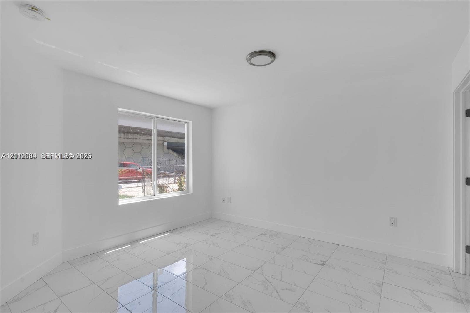1629 NW 40th Street, Miami, FL 33142 Interior space featuring white walls, large-format tile flooring with a marble-finish pattern, and a flush-mount ceiling light fixture