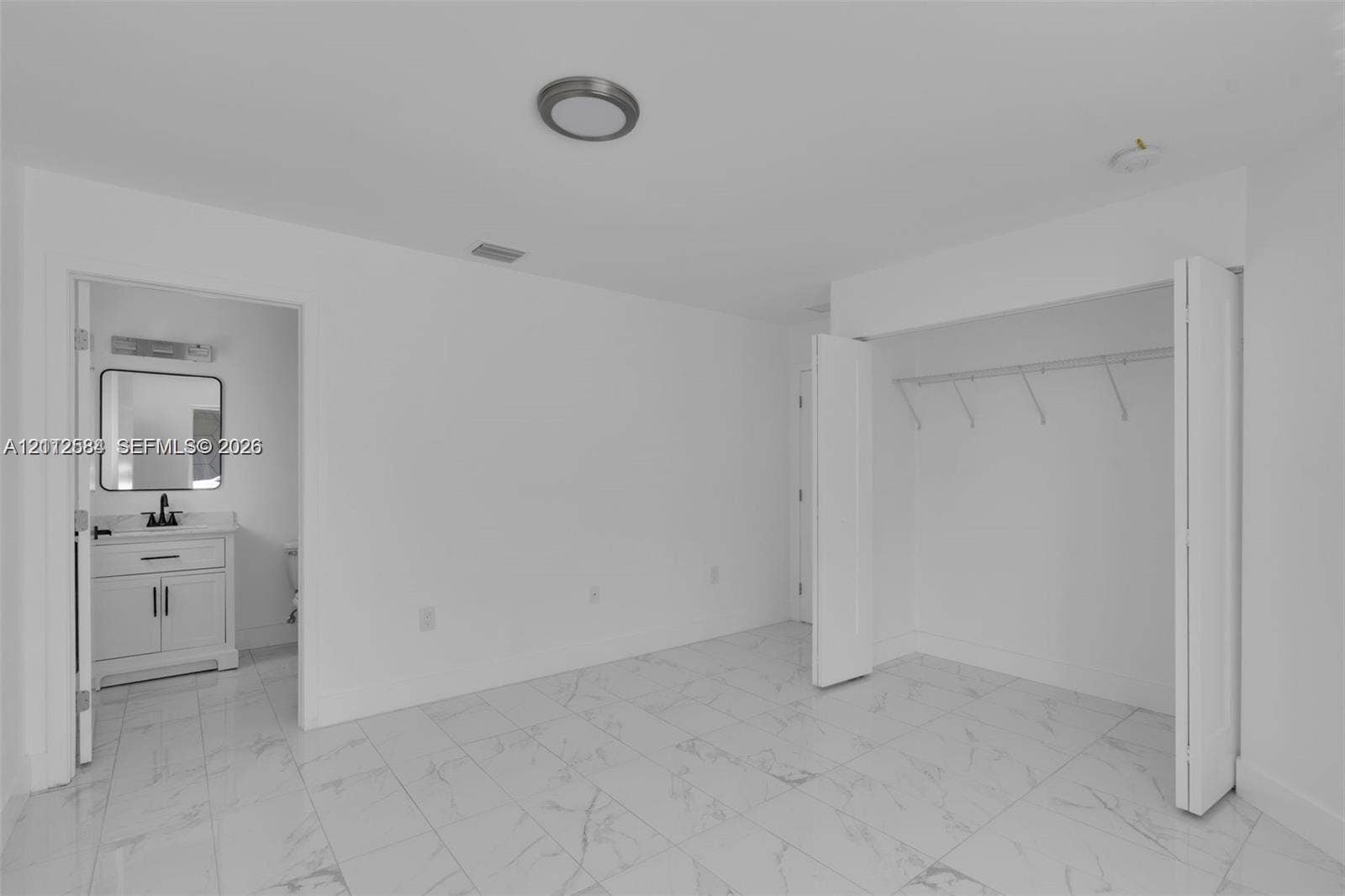 1629 NW 40th Street, Miami, FL 33142 Interior space featuring stone-finish tile flooring, a walk-in closet with built-in shelving, and a dual-door entry