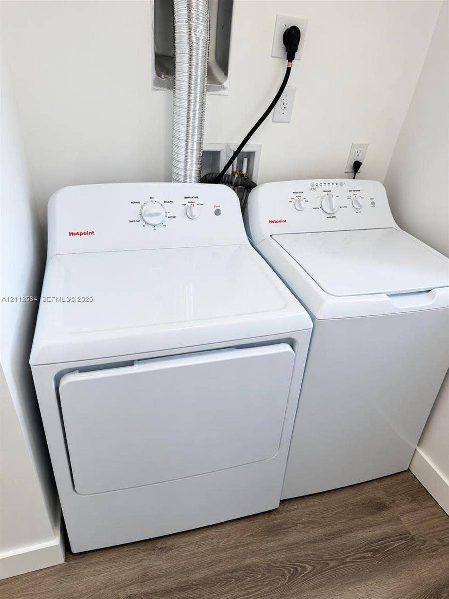 1629 NW 40th Street, Miami, FL 33142 Laundry area equipped with a top-load washing machine, front-load electric dryer, and wood-finish flooring