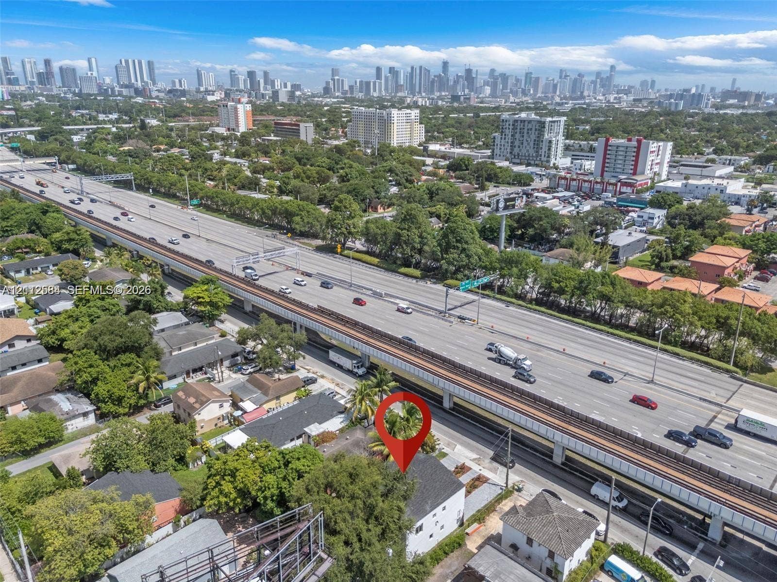 1629 NW 40th Street, Miami, FL 33142 Aerial perspective of a detached residential structure featuring a dark-toned pitched roof, white exterior siding, and mature trees within the lot boundaries
