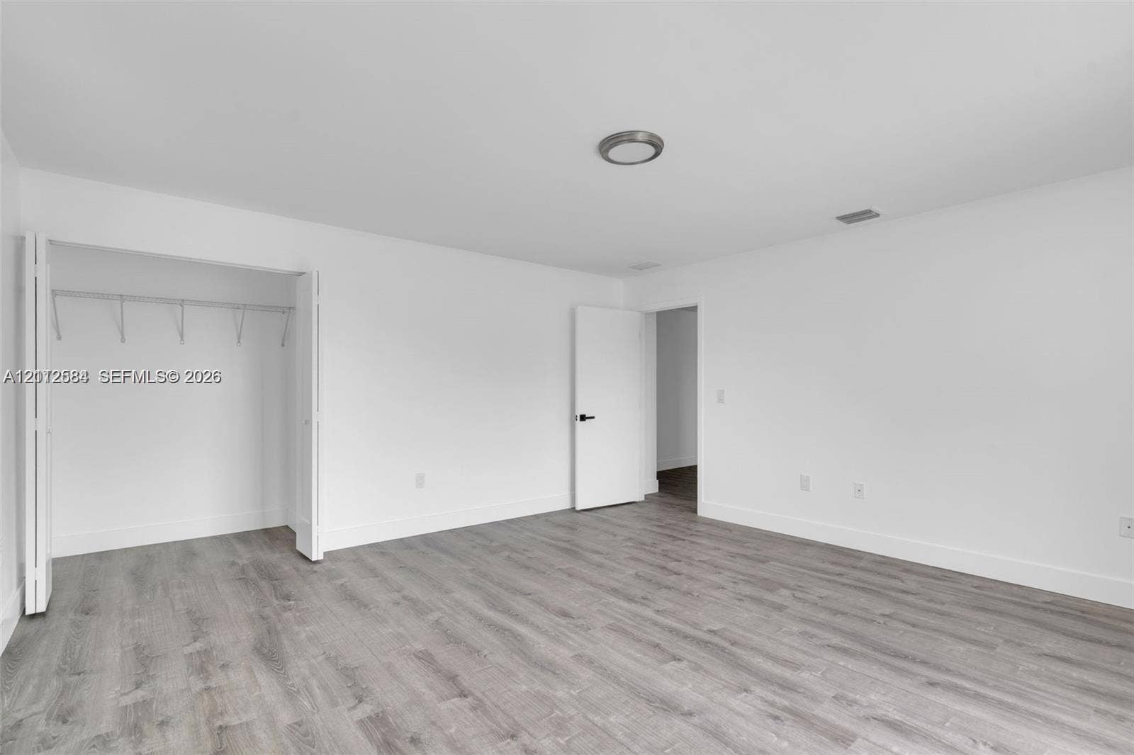 1629 NW 40th Street, Miami, FL 33142 Neutral-toned wood-finish flooring, white walls, and built-in closet storage featuring double-hinged doors and a ceiling-mounted light fixture