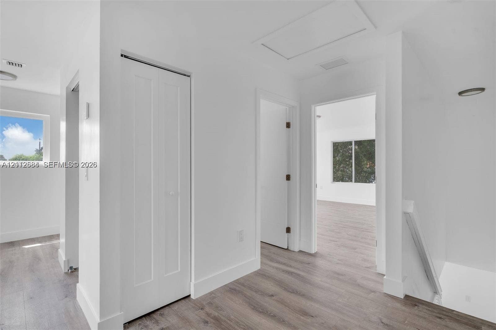1629 NW 40th Street, Miami, FL 33142 Interior hallway featuring wood-finish flooring, white walls, bi-fold closet doors, and recessed lighting