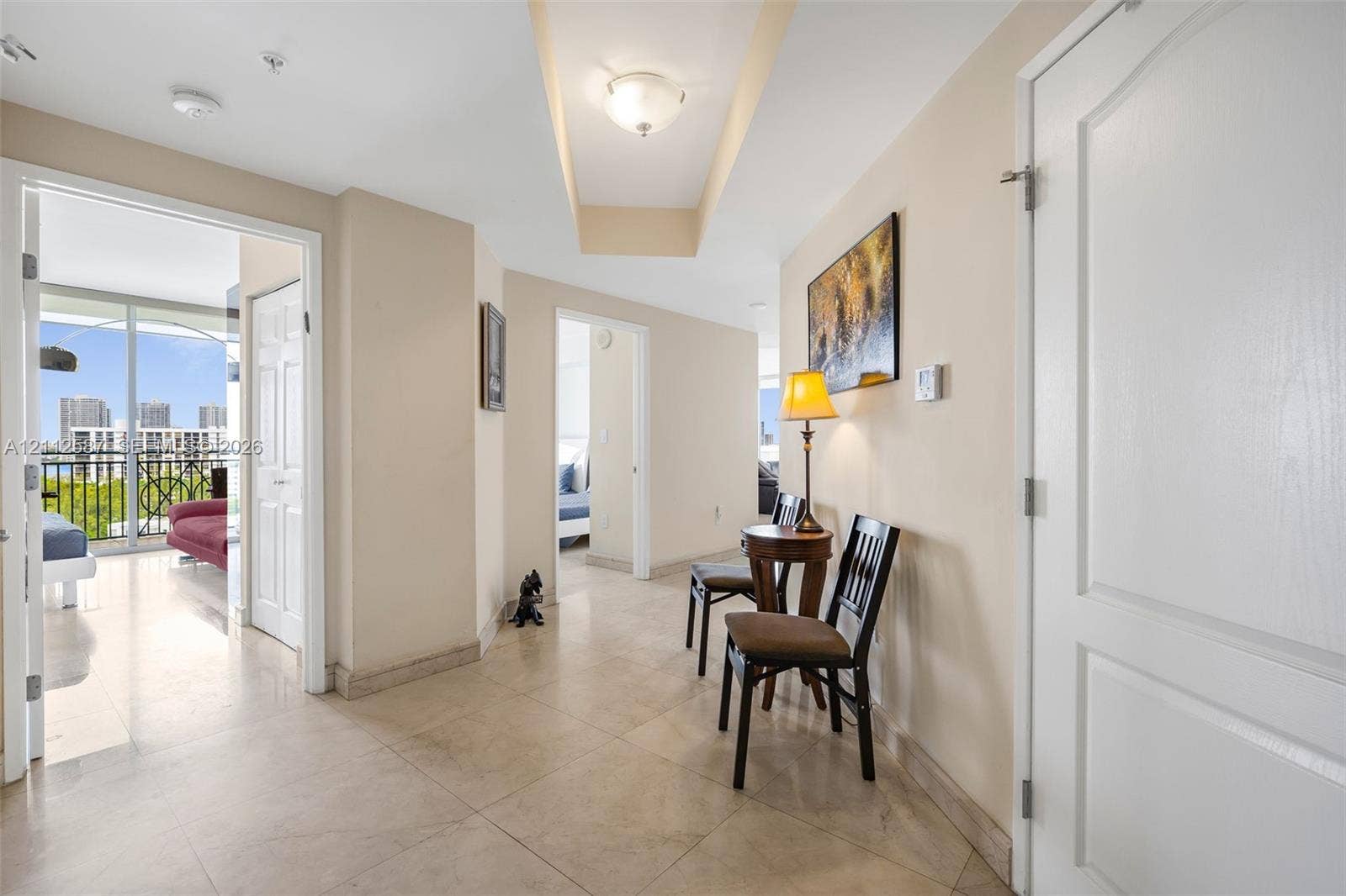 17555 NW Atlantic Boulevard, #1108, Sunny Isles Beach, FL 33160 Interior hallway featuring large-format tile flooring, a recessed tray ceiling, flush-mount lighting, and solid-core interior doors