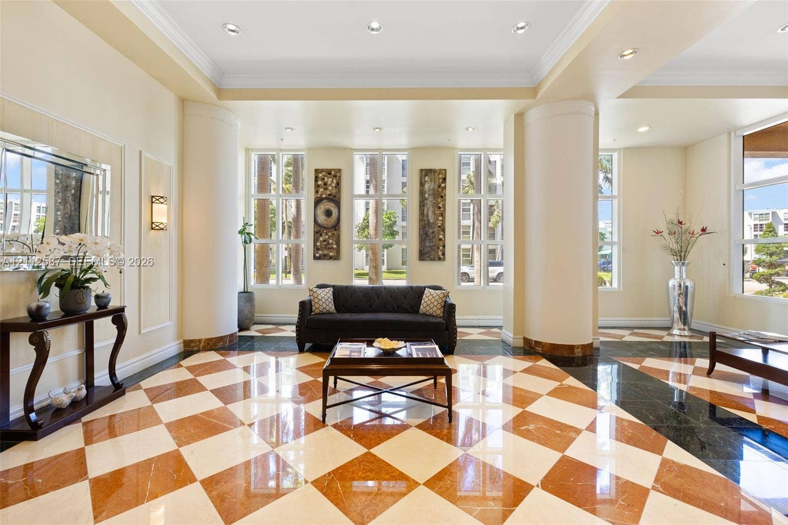 17555 NW Atlantic Boulevard, #1108, Sunny Isles Beach, FL 33160 Grand lobby featuring a checkered tile floor, recessed lighting, multi-pane floor-to-ceiling windows, and structural columns with stone-finish accents