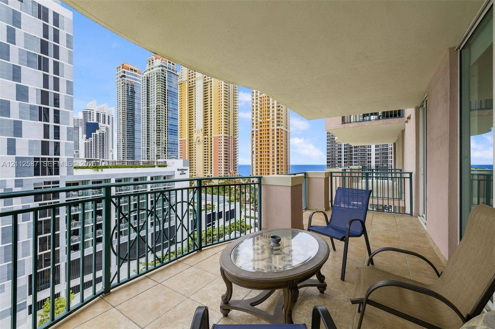 17555 NW Atlantic Boulevard, #1108, Sunny Isles Beach, FL 33160 Covered balcony featuring tile flooring and decorative metal railings with urban and coastal scenery