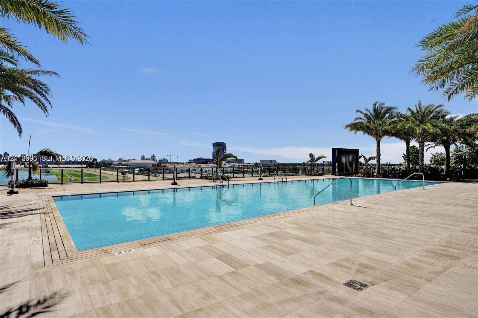 Hallandale Beach, Hallandale Beach, FL 33009 Rectangular swimming pool featuring a tile deck, metal perimeter railing, and palm tree landscaping