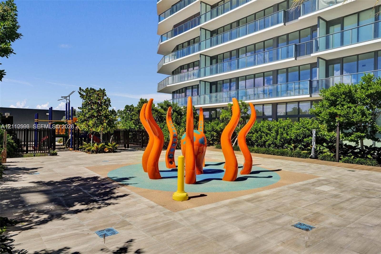 Hallandale Beach, Hallandale Beach, FL 33009 Outdoor recreation area featuring a paved terrace, colorful sculptural water feature, integrated rubberized ground surface, and perimeter landscaping