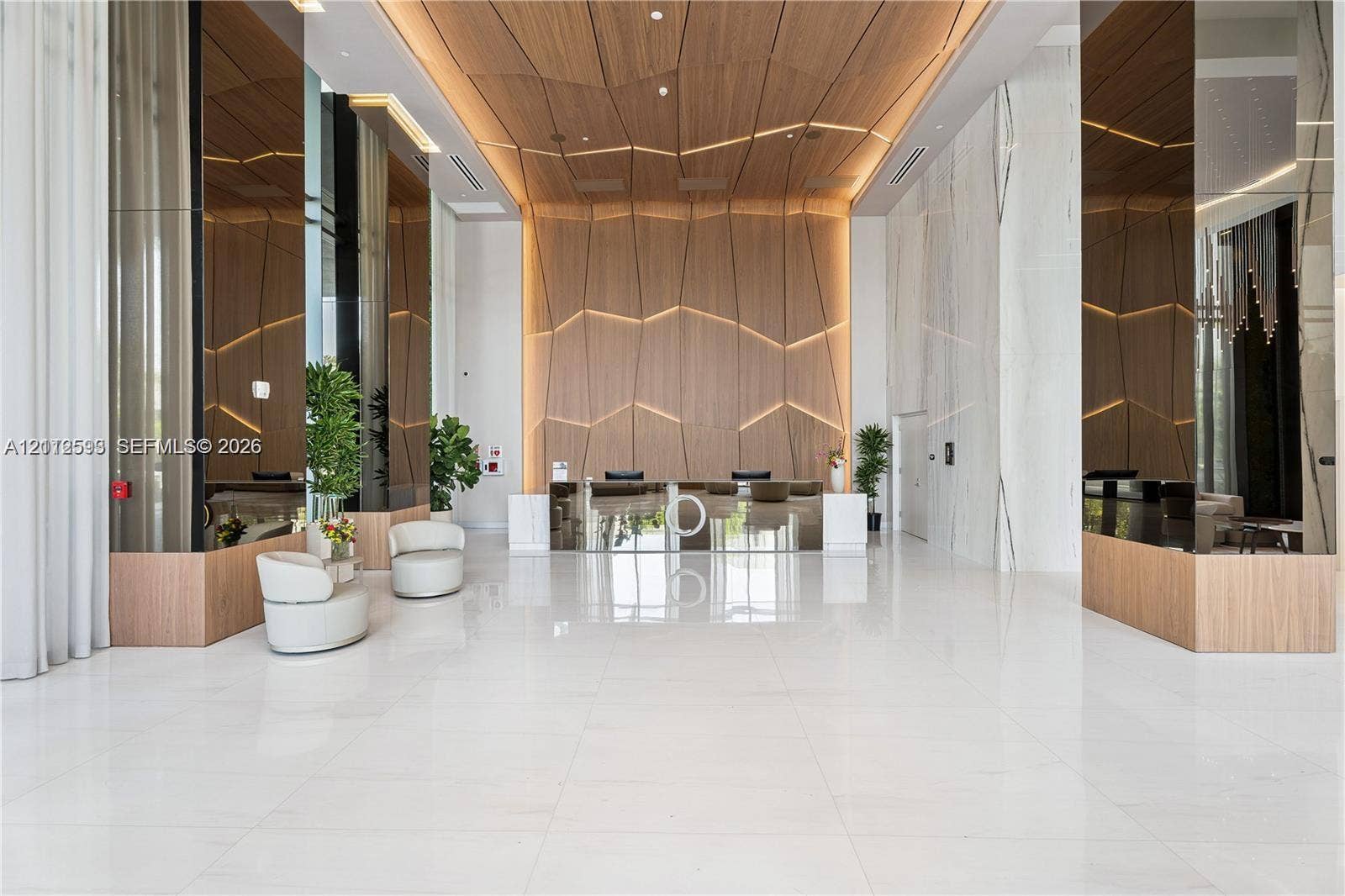 Hallandale Beach, Hallandale Beach, FL 33009 Grand lobby featuring large-format tile flooring, reflective mirror-clad columns, and a geometric wood-paneled accent wall with integrated linear lighting