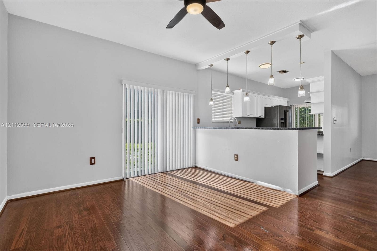 7974 NW 190th Terrace, Hialeah, FL 33015 Wood-finish flooring, breakfast bar with pendant lighting, white cabinetry, and vertical window blinds