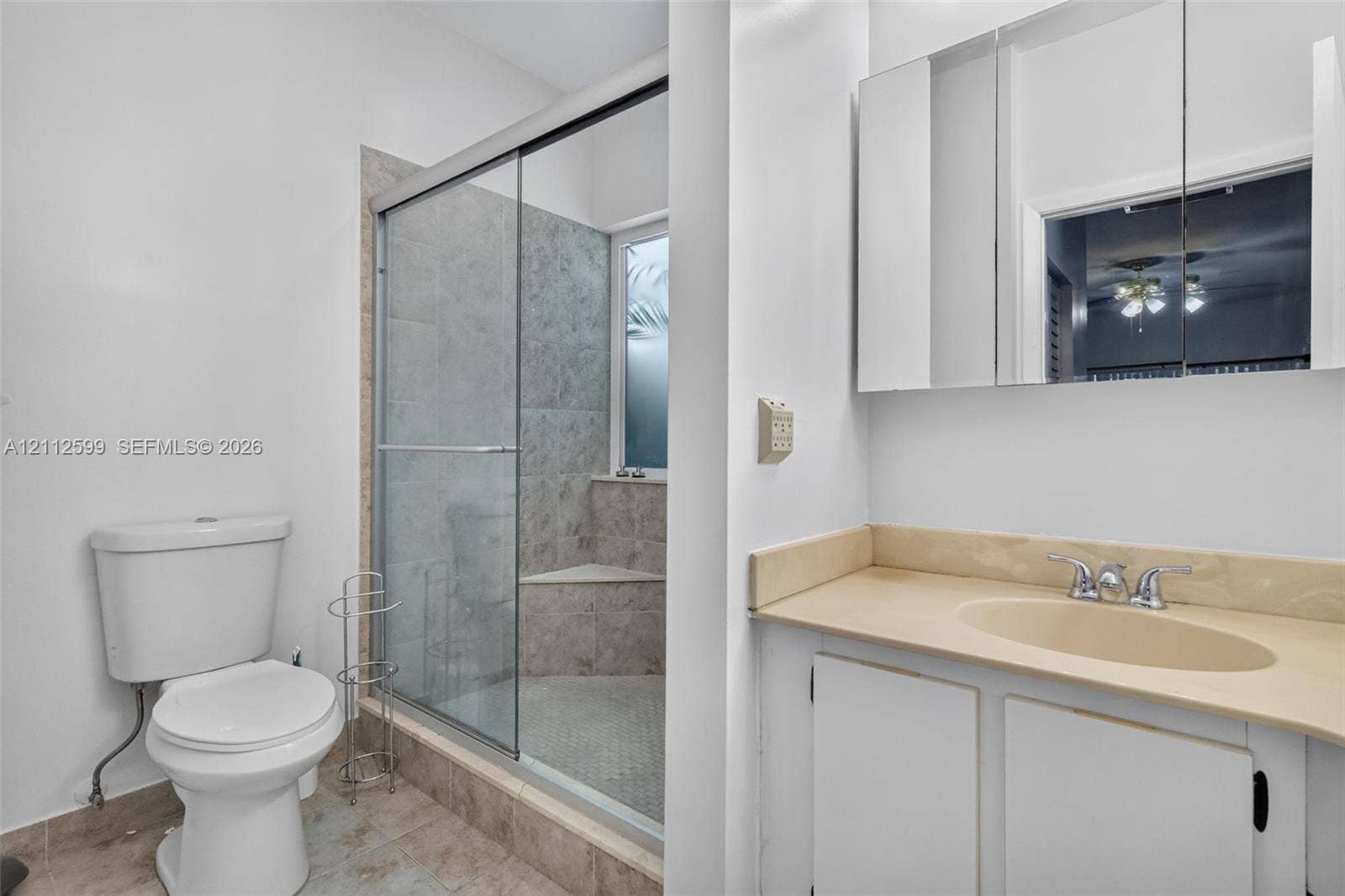 7974 NW 190th Terrace, Hialeah, FL 33015 Bathroom featuring a vanity with an integrated sink, neutral countertop, wall-mounted mirrored medicine cabinet, and a walk-in shower with a glass enclosure and tiled bench