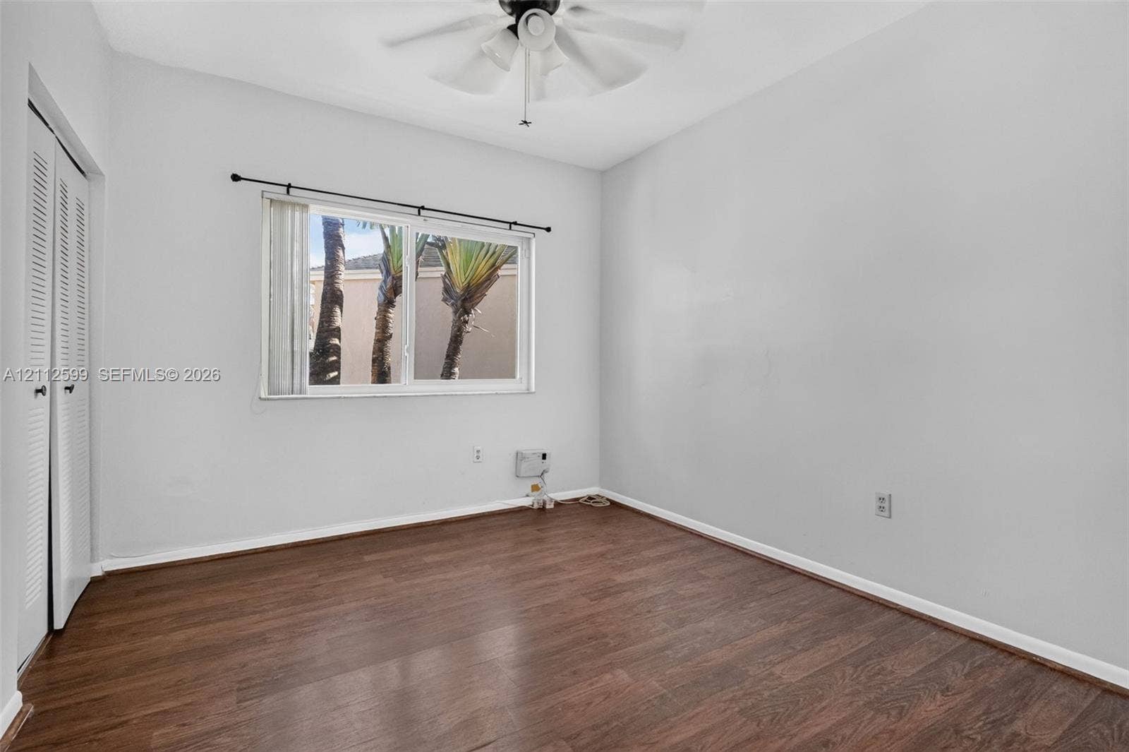 7974 NW 190th Terrace, Hialeah, FL 33015 Room featuring wood-finish flooring, a ceiling fan with integrated lighting, a sliding door closet, and a window with a curtain rod