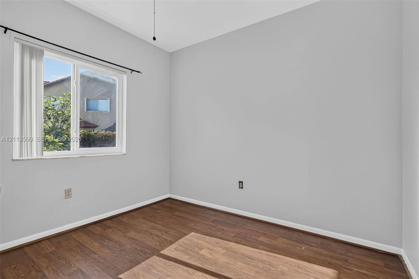 7974 NW 190th Terrace, Hialeah, FL 33015 Room featuring neutral wall tones, wood-finish flooring, and a single-pane sliding window