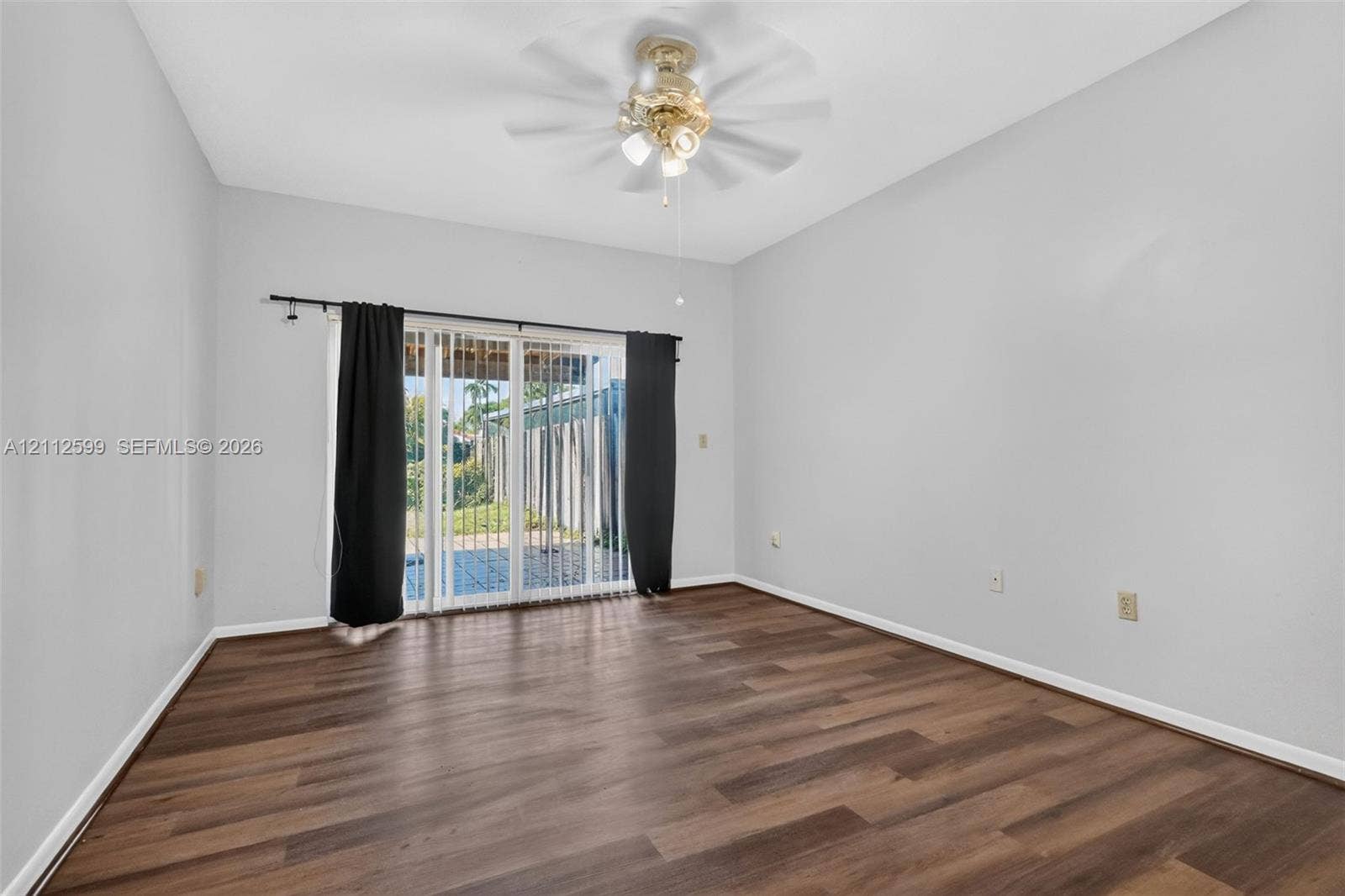 7974 NW 190th Terrace, Hialeah, FL 33015 Room featuring wood-finish flooring, sliding glass doors, and a ceiling-mounted light fixture with a multi-blade fan
