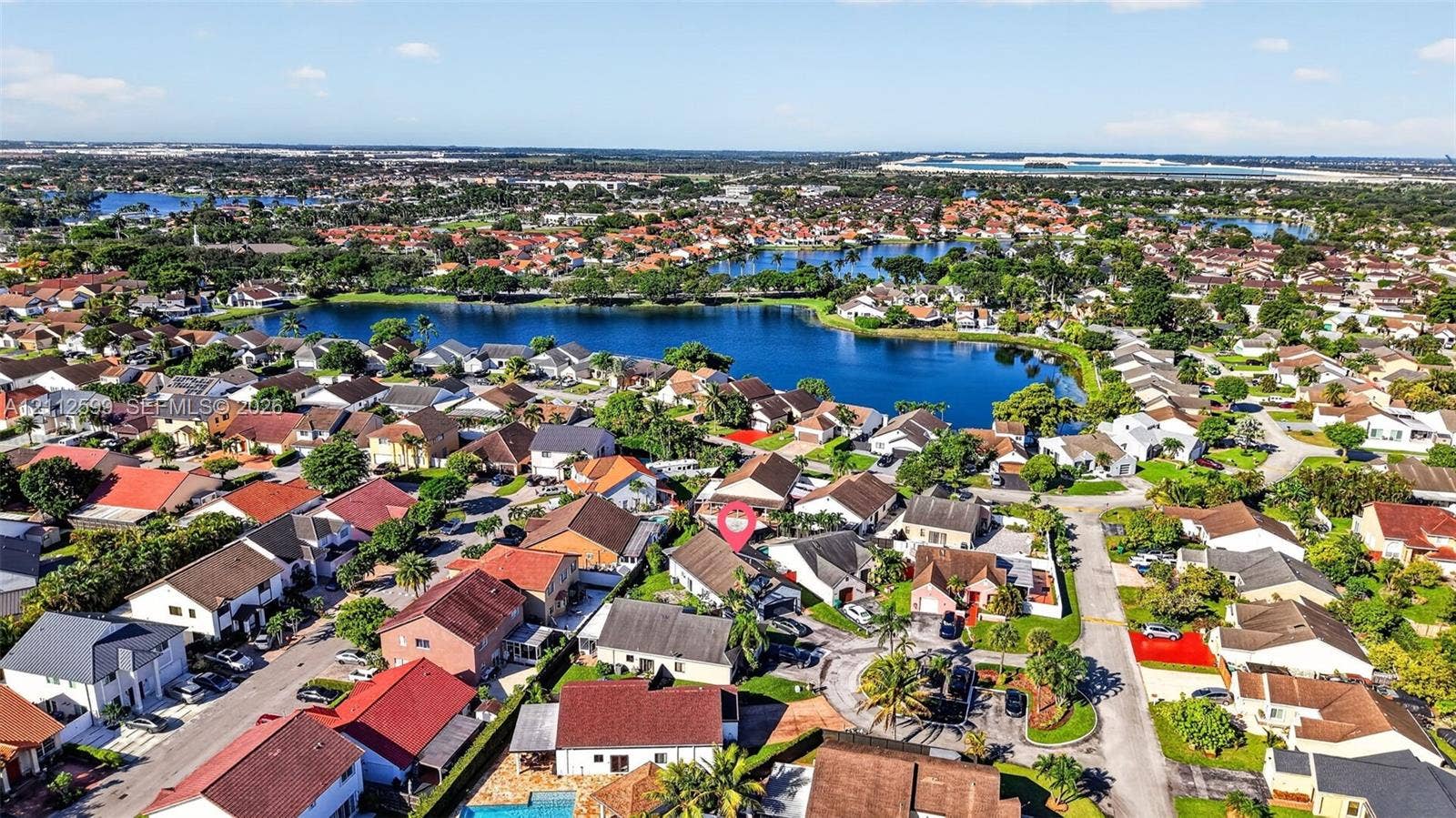 7974 NW 190th Terrace, Hialeah, FL 33015 Aerial perspective of a suburban lot featuring mature palm trees and direct proximity to a community lake
