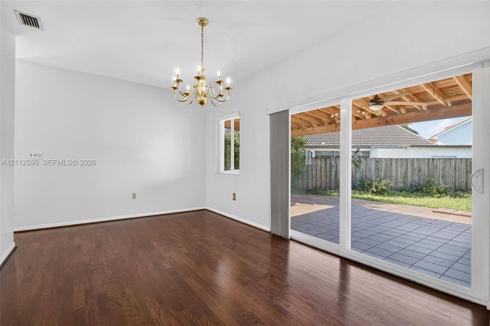 7974 NW 190th Terrace, Hialeah, FL 33015 Wood-finish flooring, multi-light chandelier, sliding glass door, and exterior paved patio with wood pergola