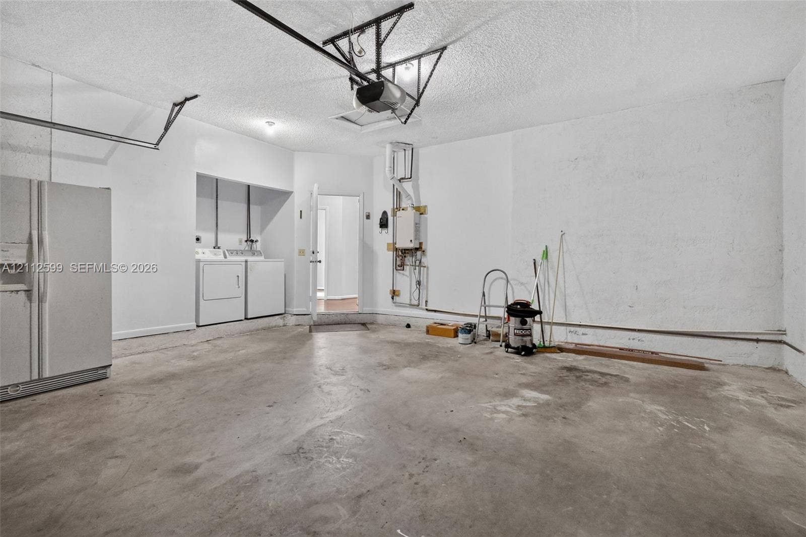 7974 NW 190th Terrace, Hialeah, FL 33015 Garage featuring concrete flooring, built-in laundry hookups, and a tankless water heater