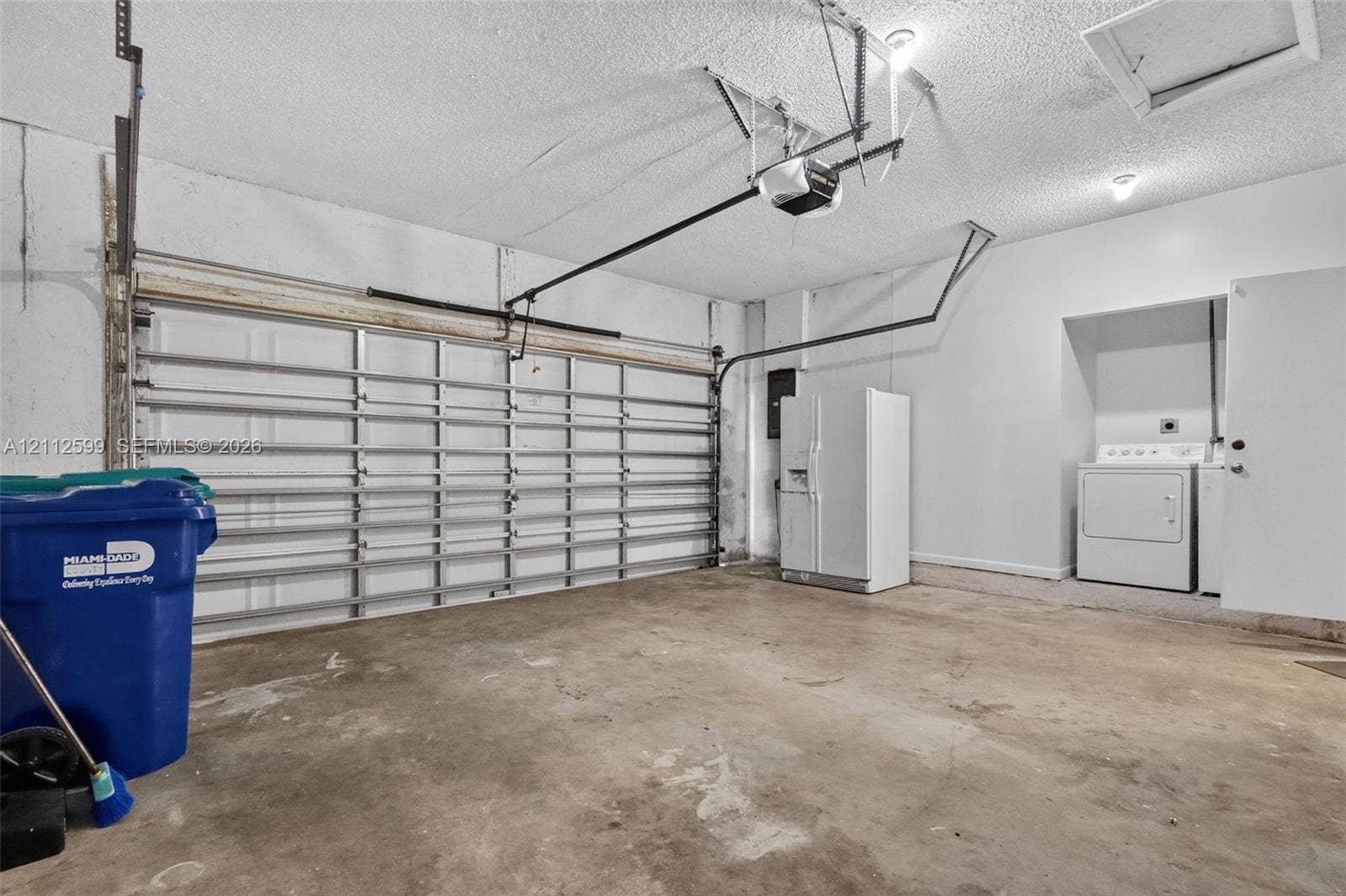 7974 NW 190th Terrace, Hialeah, FL 33015 Enclosed two-car garage featuring a sectional overhead door, automatic door opener, concrete flooring, and an integrated laundry utility area