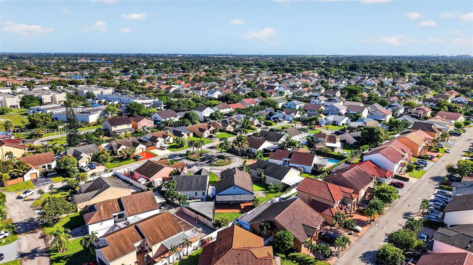 7974 NW 190th Terrace, Hialeah, FL 33015 Aerial perspective of a suburban neighborhood featuring paved streets, established residential lots, mature landscaping, and diverse roofline profiles