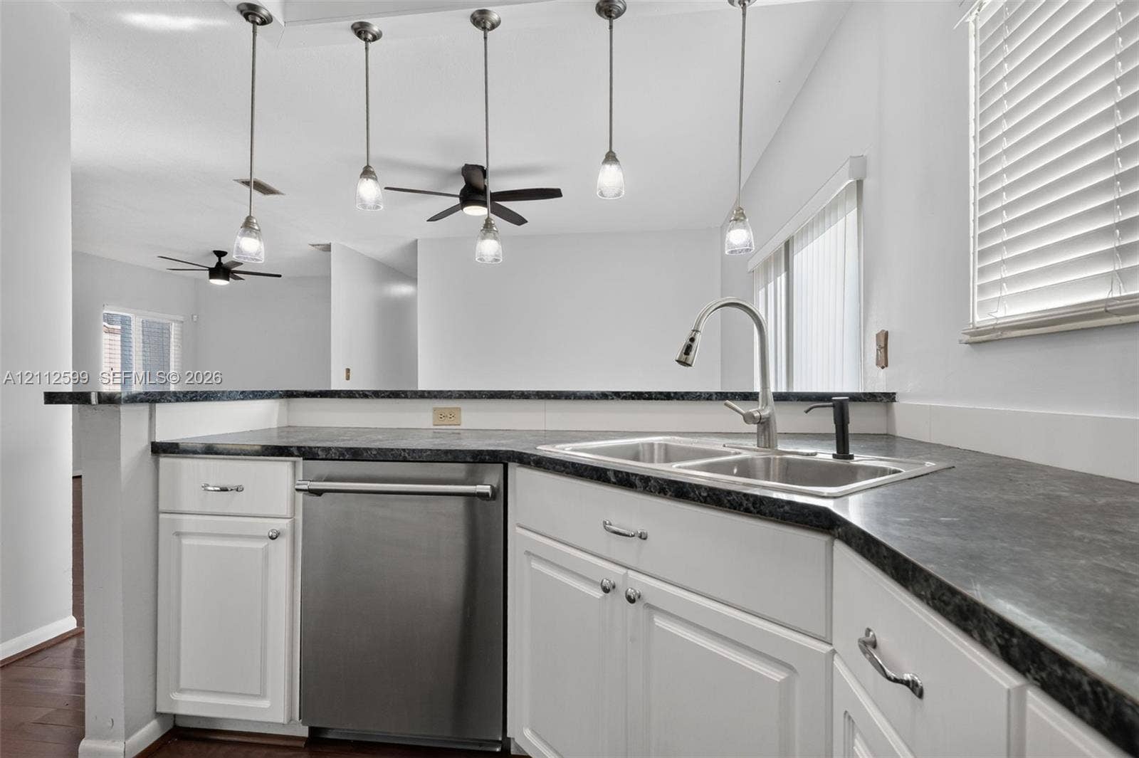 7974 NW 190th Terrace, Hialeah, FL 33015 Kitchen featuring white cabinetry, dark stone-finish countertops, stainless steel dishwasher, dual-basin sink with pull-down faucet, and four glass pendant lights