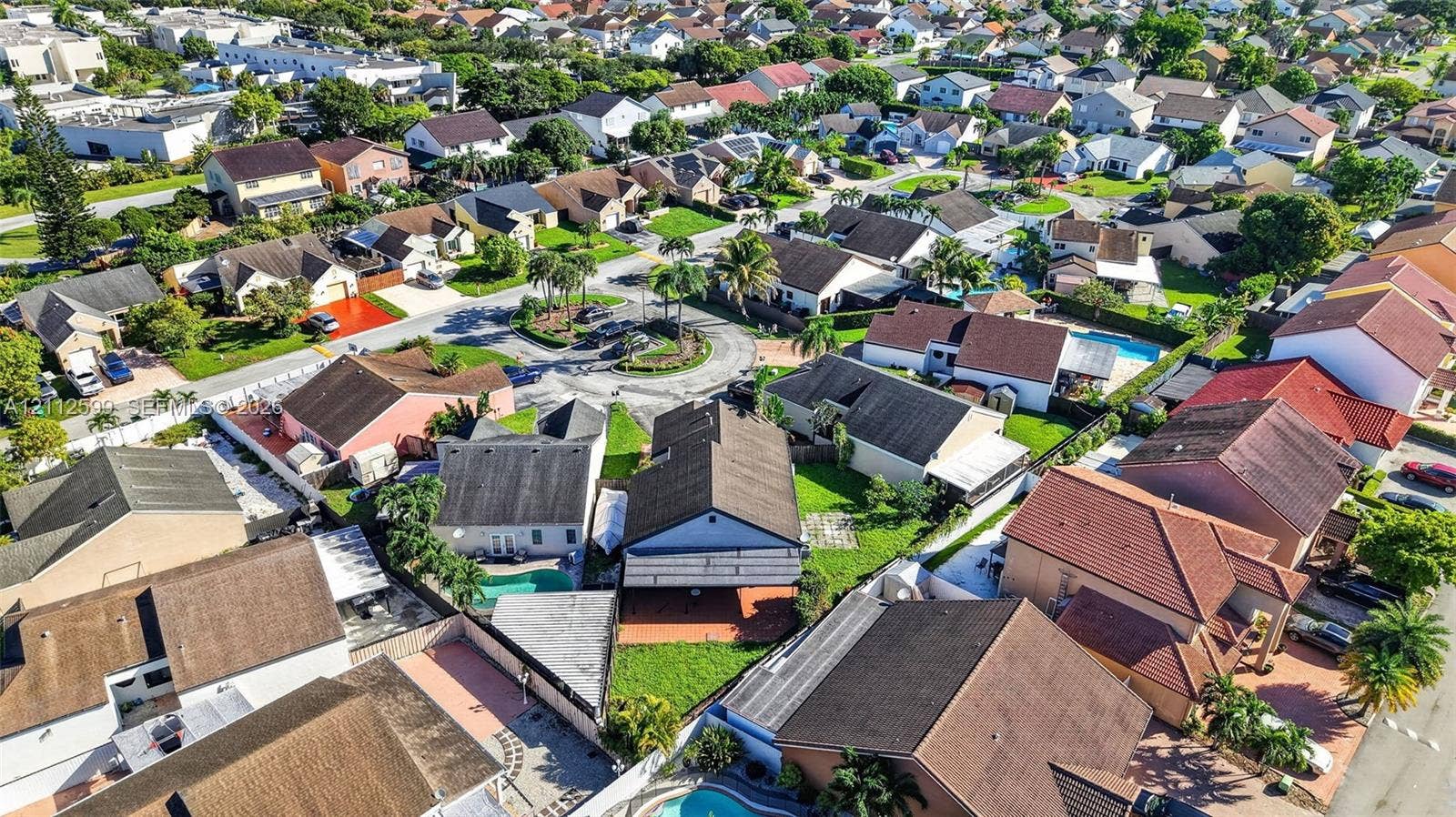 7974 NW 190th Terrace, Hialeah, FL 33015 Aerial perspective of a residential neighborhood featuring multiple low-rise dwellings with tile roofing and paved driveways, surrounded by mature palm trees and manicured lawns
