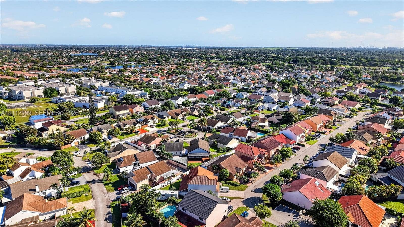 7974 NW 190th Terrace, Hialeah, FL 33015 Aerial perspective of a suburban neighborhood featuring residential rooftops, paved street infrastructure, mature landscaping, and interspersed green space