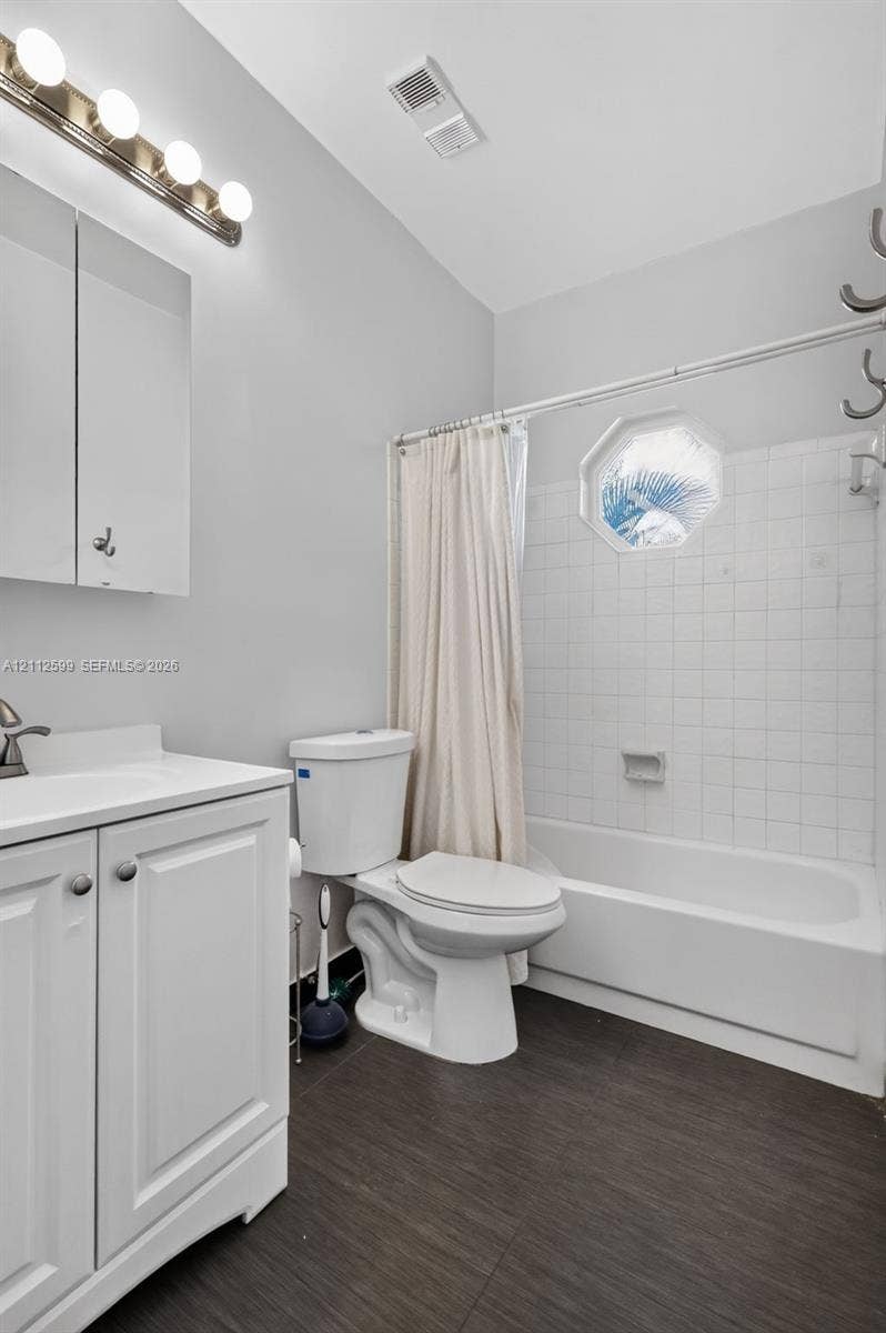 7974 NW 190th Terrace, Hialeah, FL 33015 Bathroom featuring a white vanity cabinet, four-light vanity fixture, bathtub with tiled surround, and octagonal window