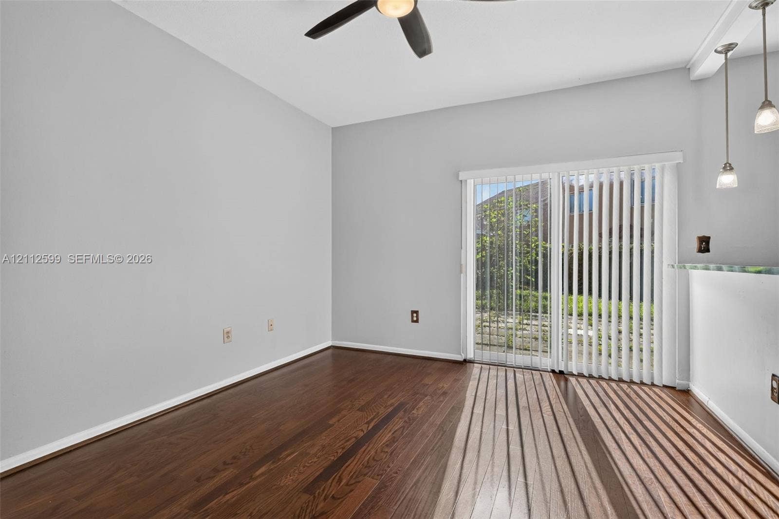 7974 NW 190th Terrace, Hialeah, FL 33015 Room featuring wood-finish flooring, sliding glass doors with vertical blinds, a ceiling fan, and pendant lighting