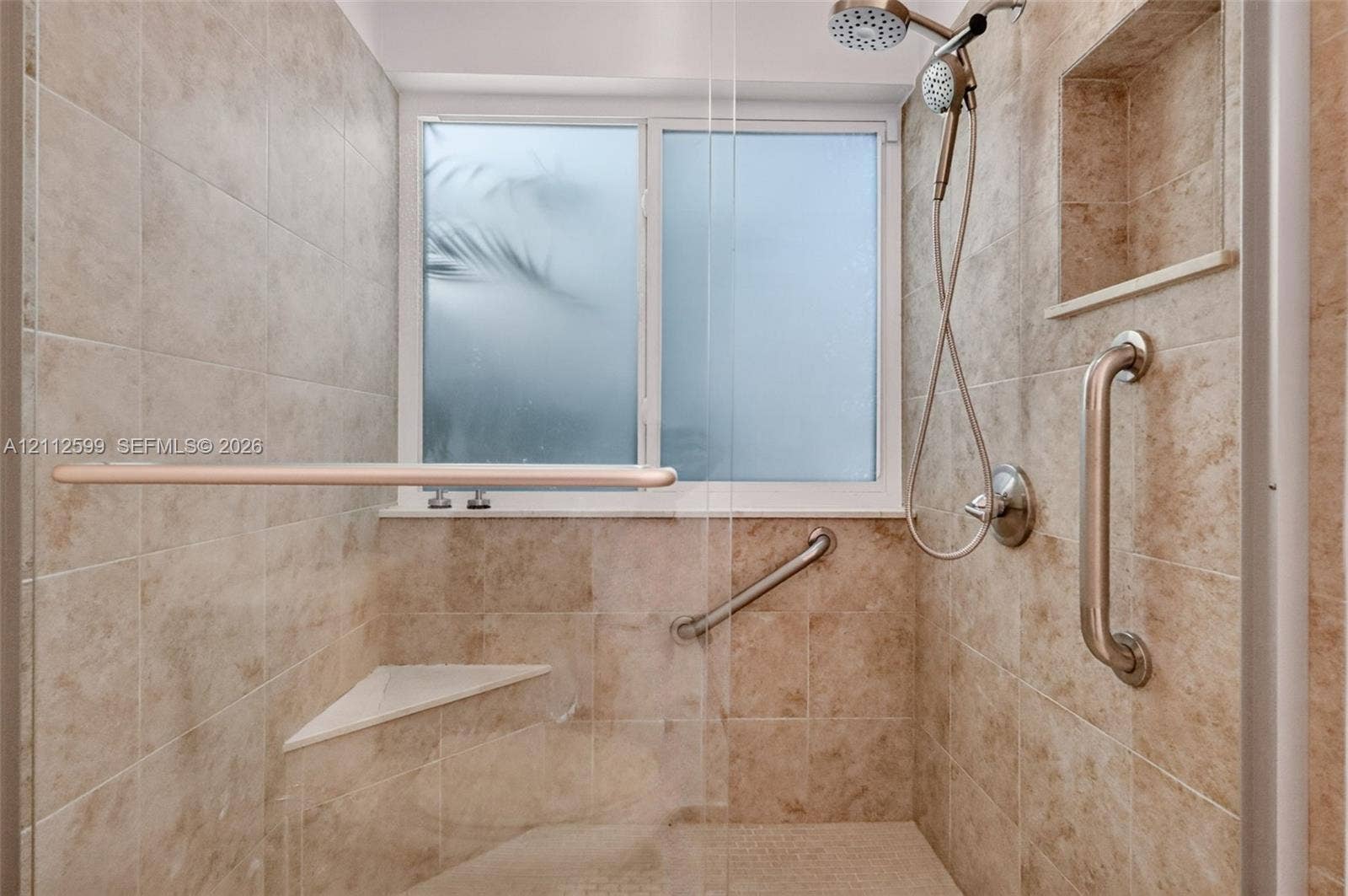 7974 NW 190th Terrace, Hialeah, FL 33015 Walk-in shower featuring floor-to-ceiling stone-finish tile, a built-in corner bench, a recessed wall niche, a sliding shower head, and metal grab bars