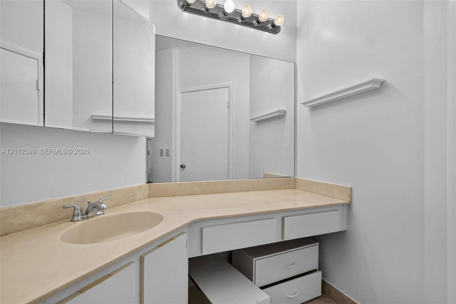 7974 NW 190th Terrace, Hialeah, FL 33015 Built-in vanity featuring a solid surface countertop, integrated sink, multi-drawer storage, large wall-mounted mirror, and multi-bulb vanity light fixture