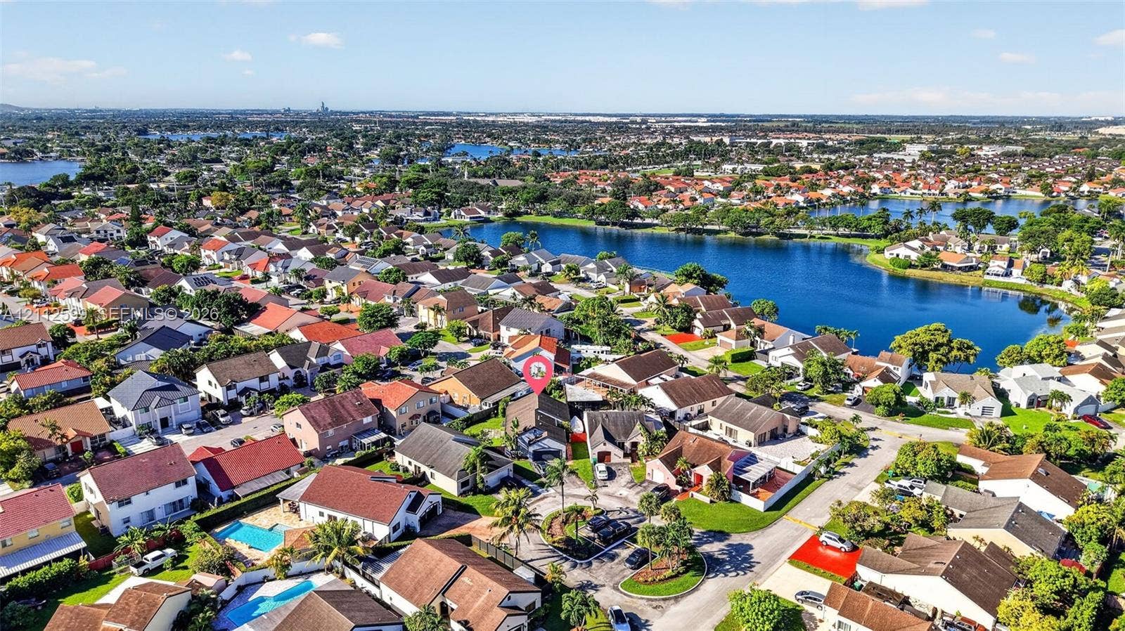 7974 NW 190th Terrace, Hialeah, FL 33015 Aerial perspective featuring a residential property situated in a suburban neighborhood with water frontage and mature landscaping