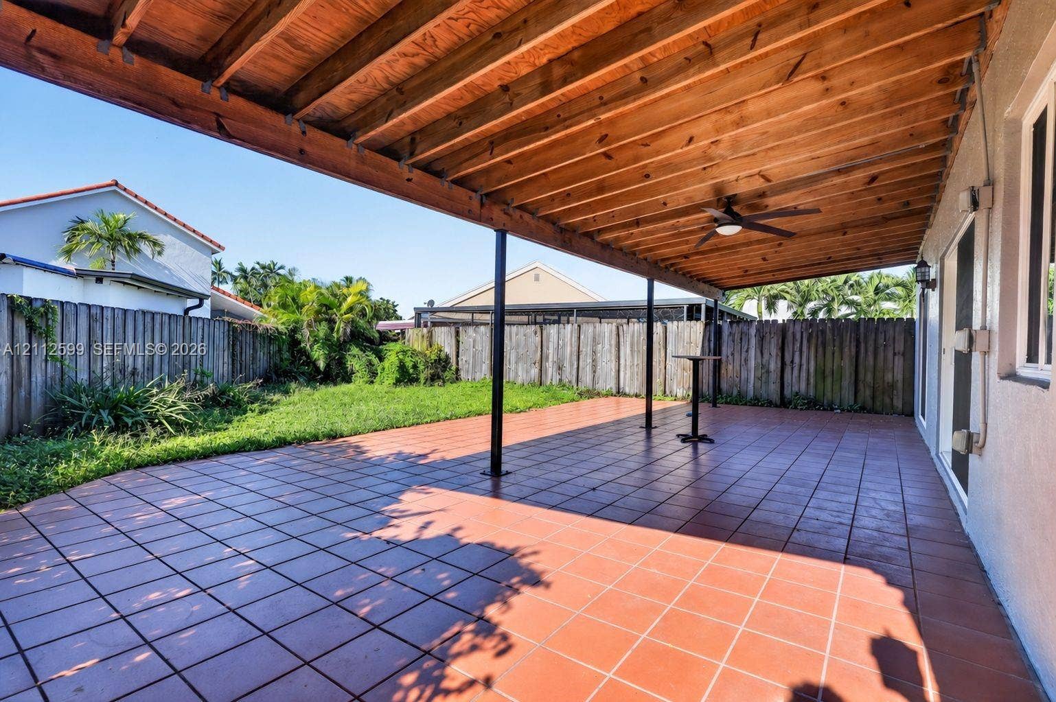 7974 NW 190th Terrace, Hialeah, FL 33015 Covered outdoor patio featuring tile flooring, a natural wood-finish ceiling with an integrated ceiling fan, and fenced backyard grounds