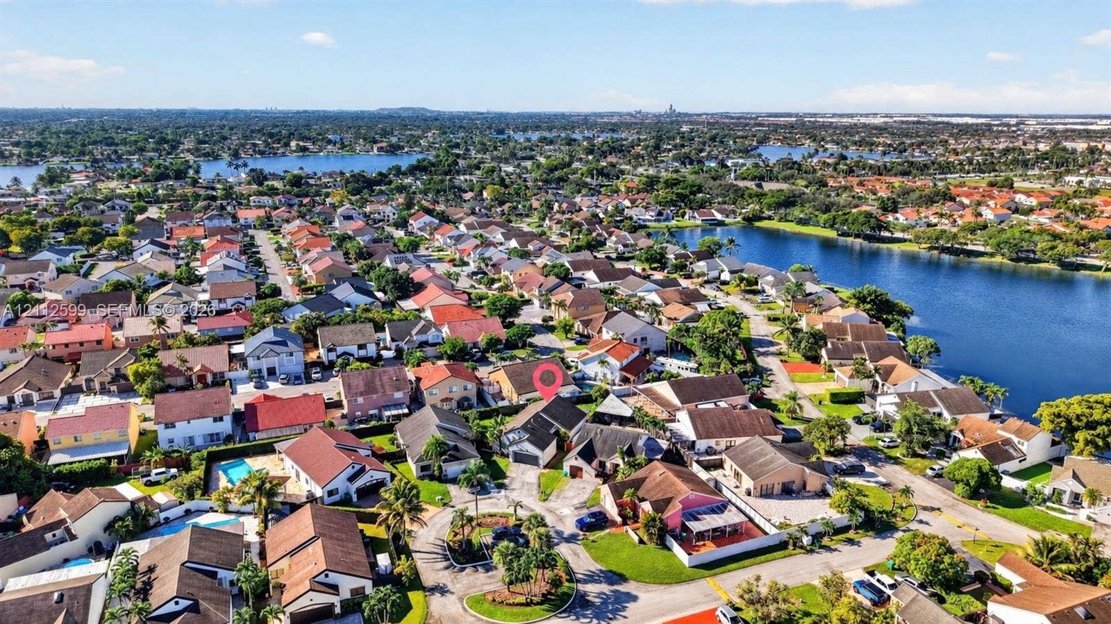 7974 NW 190th Terrace, Hialeah, FL 33015 Aerial perspective featuring a residential lot situated within a waterfront community, including access to local canal systems and established mature landscaping