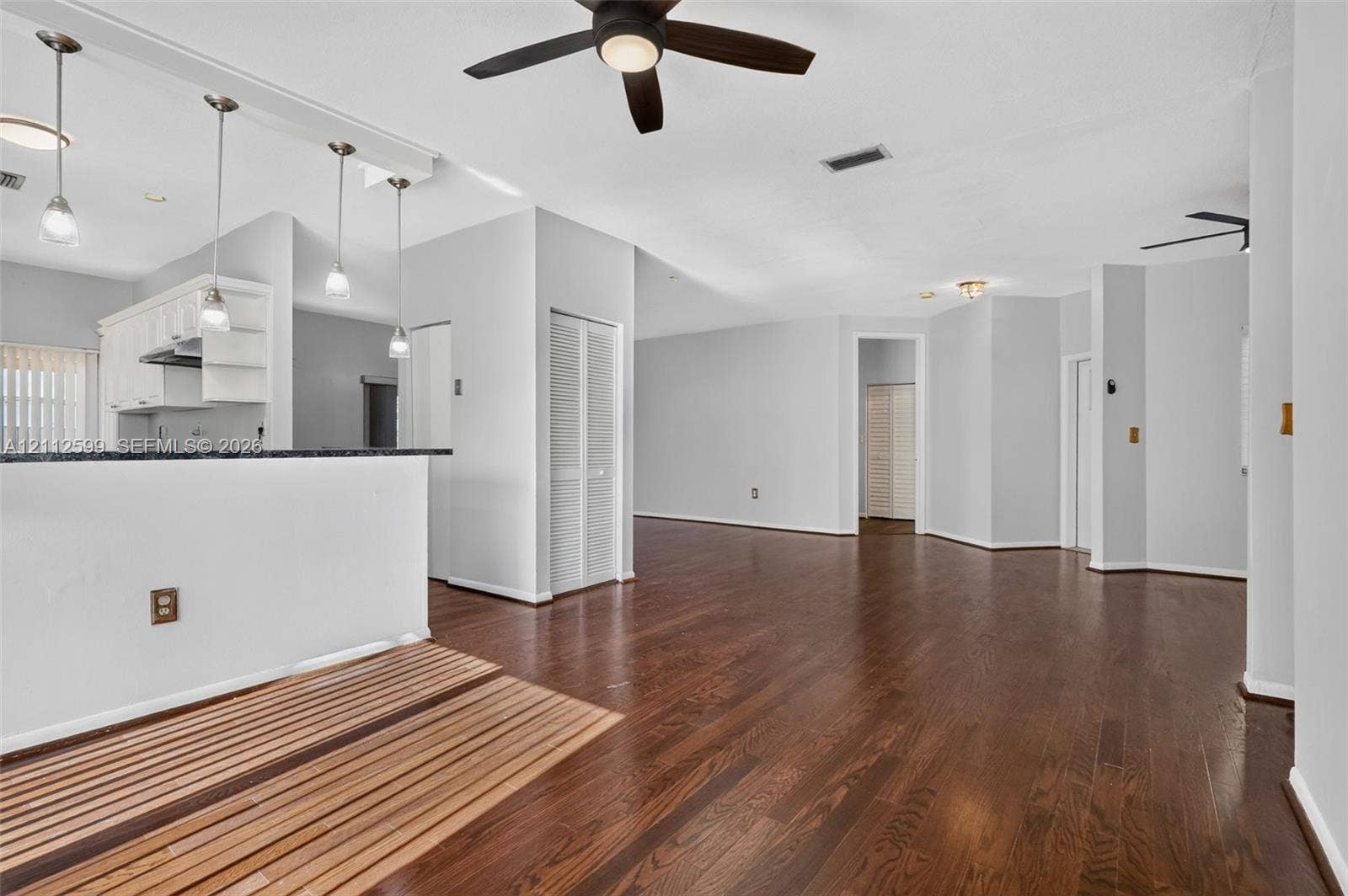 7974 NW 190th Terrace, Hialeah, FL 33015 Open floor plan featuring wood-finish flooring, a kitchen peninsula with pendant lighting, and ceiling fan fixtures