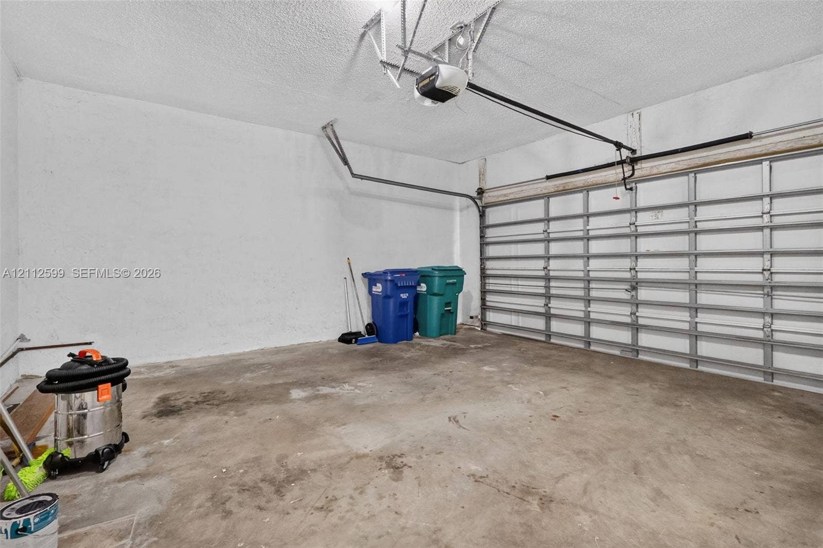 7974 NW 190th Terrace, Hialeah, FL 33015 Enclosed garage featuring a concrete floor, textured ceiling, and automatic sectional garage door opener