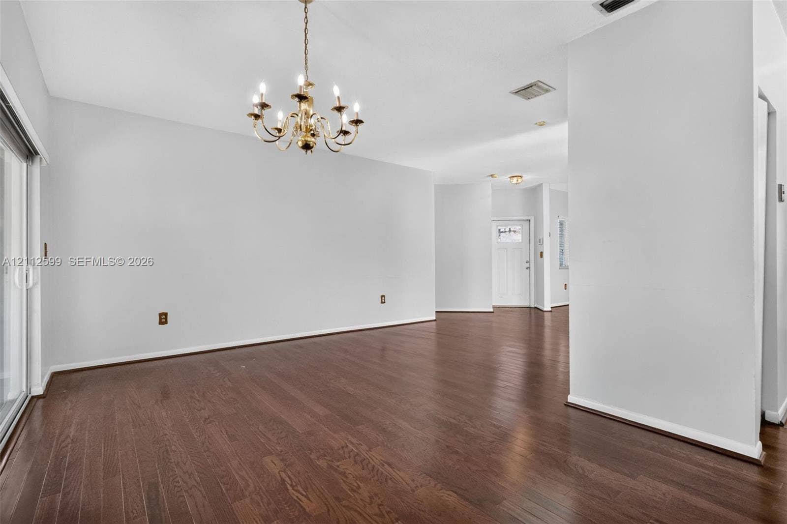 7974 NW 190th Terrace, Hialeah, FL 33015 Open-concept interior featuring wood-finish flooring, a multi-arm chandelier, and sliding glass doors