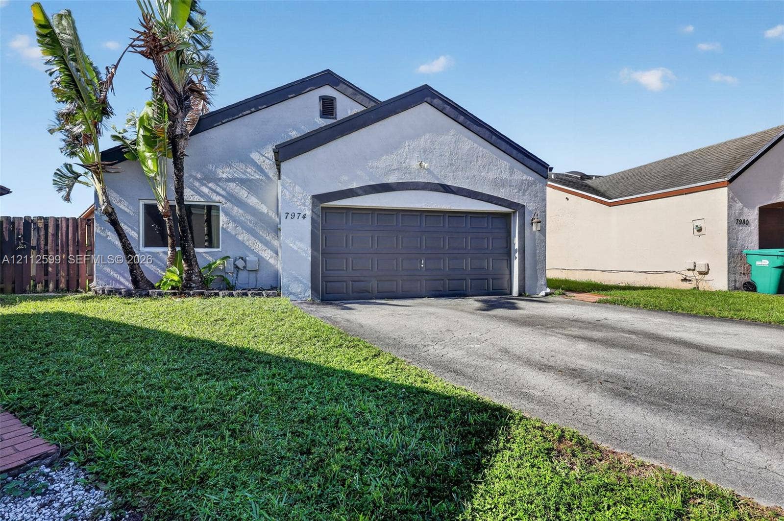 7974 NW 190th Terrace, Hialeah, FL 33015 Stucco exterior with an arched entryway, single-car garage, asphalt driveway, and mature landscaping