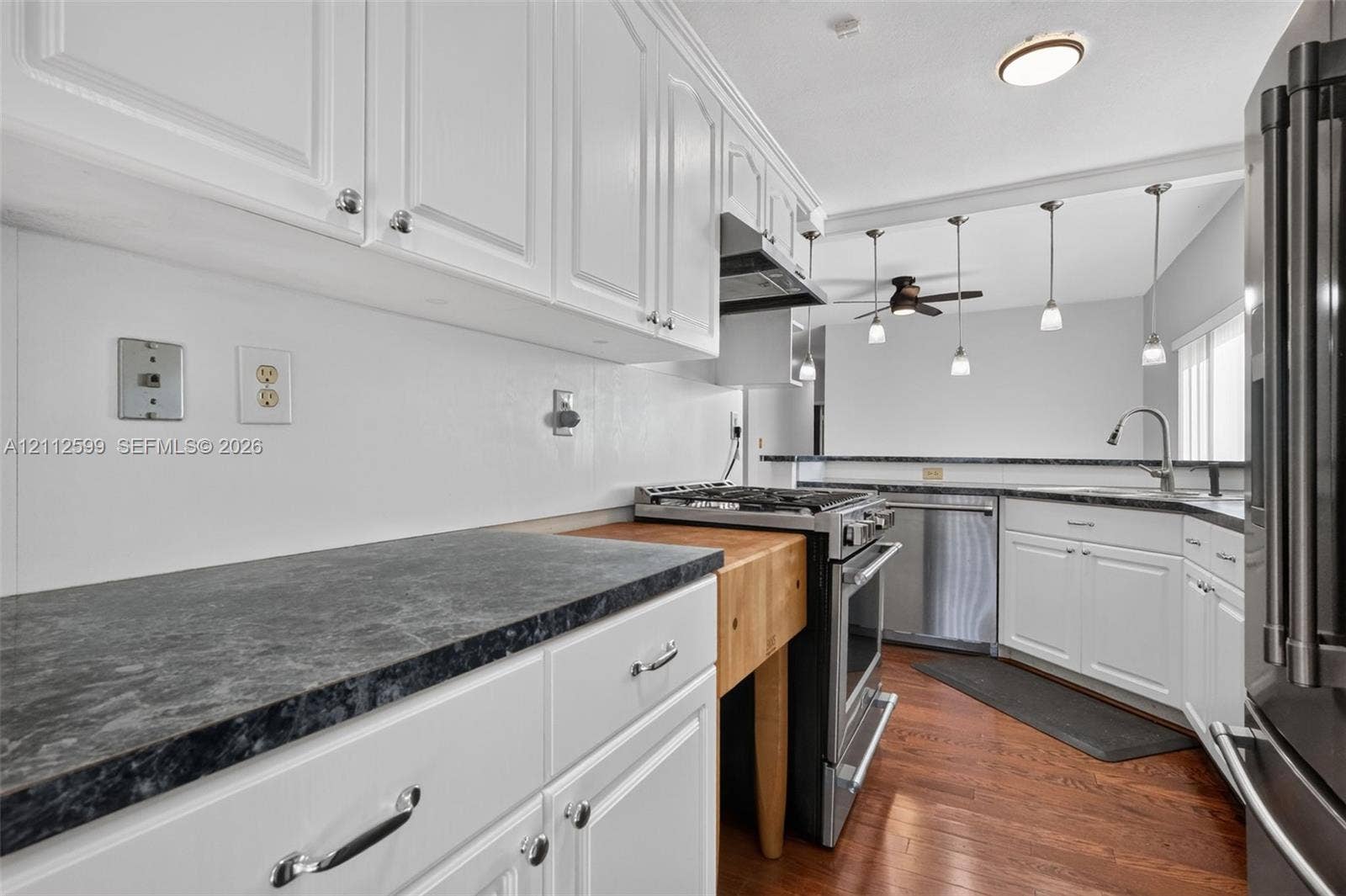 7974 NW 190th Terrace, Hialeah, FL 33015 Kitchen featuring white cabinetry, dark countertops, integrated butcher-block prep station, stainless steel appliances, and wood-finish flooring