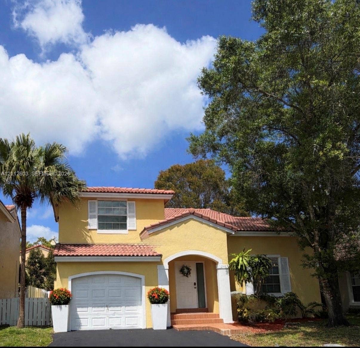 Stucco exterior featuring a terracotta tile roof, arched entryway, single-car garage and driveway for additional 2 cars